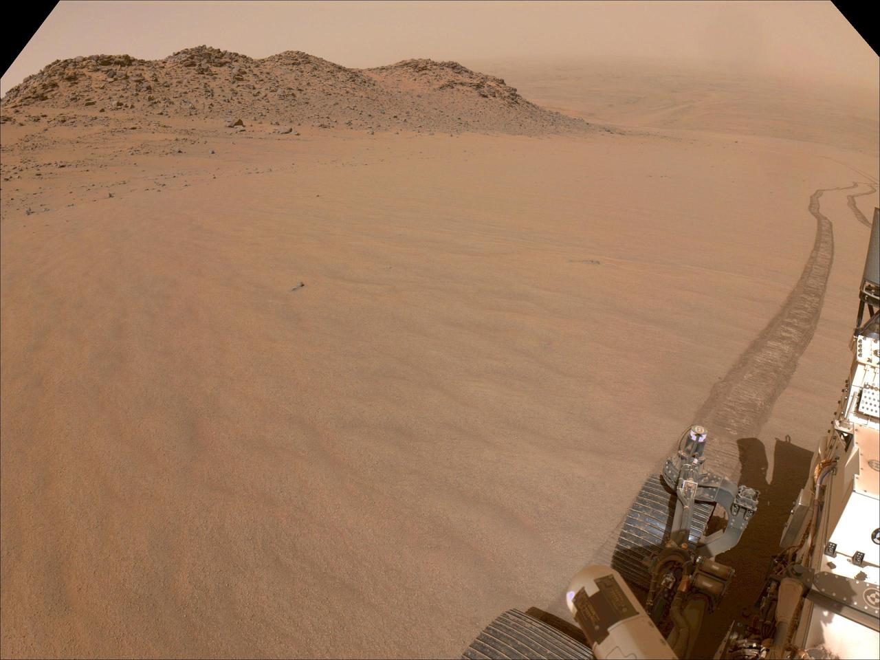 NASA's Perseverance Mars rover used its navigation cameras, or navcams, to capture this scene while driving up to Jezero Crater's rim on Nov. 11, 2024, the 1,326th Martian day, or sol, of the mission. The sandy terrain seen here, along with a 10-degree average slope, meant it was a slippery drive. Rover tracks trail off behind Perseverance in this image. Far in the distance is the floor of Jezero Crater. A key objective for Perseverance's mission on Mars is astrobiology, including the search for signs of ancient microbial life. The rover will characterize the planet's geology and past climate, pave the way for human exploration of the Red Planet, and be the first mission to collect and cache Martian rock and regolith (broken rock and dust). Subsequent NASA missions, in cooperation with ESA (European Space Agency), would send spacecraft to Mars to collect these sealed samples from the surface and return them to Earth for in-depth analysis. The Mars 2020 Perseverance mission is part of NASA's Moon to Mars exploration approach, which includes Artemis missions to the Moon that will help prepare for human exploration of the Red Planet. https://photojournal.jpl.nasa.gov/catalog/PIA26479