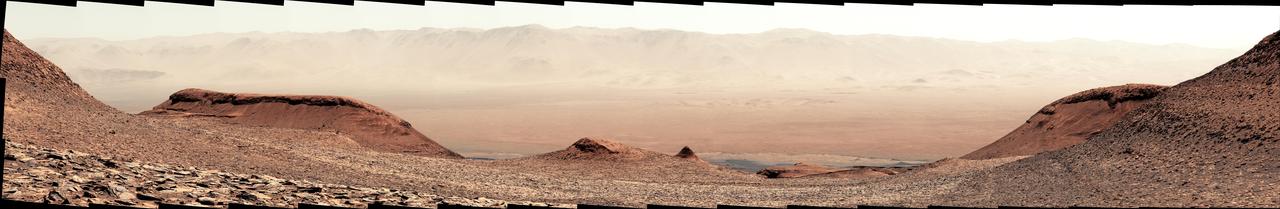 NASA's Curiosity Mars rover captured this view looking back down at the floor of Gale Crater from its location on Mount Sharp on Feb. 7, 2025, the 4,447th Martian day, or sol, of the mission. Curiosity was continuing its climb through a region of the mountain called the sulfate-bearing unit.  Mount Sharp is a 3-mile-tall (5-kilometer-tall) mountain made up of a number of layers, all of which formed in different eras of Martian history. By studying each layer, the rover's team can learn more about how the Martian environment changed over time from a warmer, wetter, and more Earthlike world to the freezing desert it is today.  The mountain is inside of Gale Crater, formed by an ancient asteroid impact. What appears to be a mountain range in the distance of this scene is in fact the crater's rim.  The color in these images has been adjusted to match the lighting conditions as the human eye would see them on Earth.  https://photojournal.jpl.nasa.gov/catalog/PIA26551