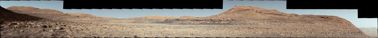 NASA's Curiosity Mars rover used its Mast Camera, or Mastcam, to capture this panorama in morning light on March 9, 2025, the 4,476th Martian day, or sol, of the mission. Steep hills on the left side of the panorama enclose wind-carved valleys on Mount Sharp, the mountain that Curiosity has been climbing for over a decade. Broken-up, rounded rocks throughout the foreground are part of the mountain's sulfate-bearing unit.  The butte in the distance at right is nicknamed "Gould Mesa." A band of cliffs and dark ridges near the top of the butte may be the first glimpses of boxwork formations, a kind of feature created by groundwater flowing through large bedrock fractures in the ancient past. Assuming that is how they formed, these could represent the last gasps of water found on this region of Mars before the planet dried out completely.  Before now, these features had only been viewed from orbiting spacecraft, to which they appeared as spiderweb-like fractures. This pattern of fractures stretches as long as 6 to 12 miles (10 to 20 kilometers) across the side of Mount Sharp. The rover's team expects to study these formations up close throughout the rest of 2025.  The color in this image has been adjusted to match lighting conditions as the human eye would see them on Earth.  https://photojournal.jpl.nasa.gov/catalog/PIA26552 