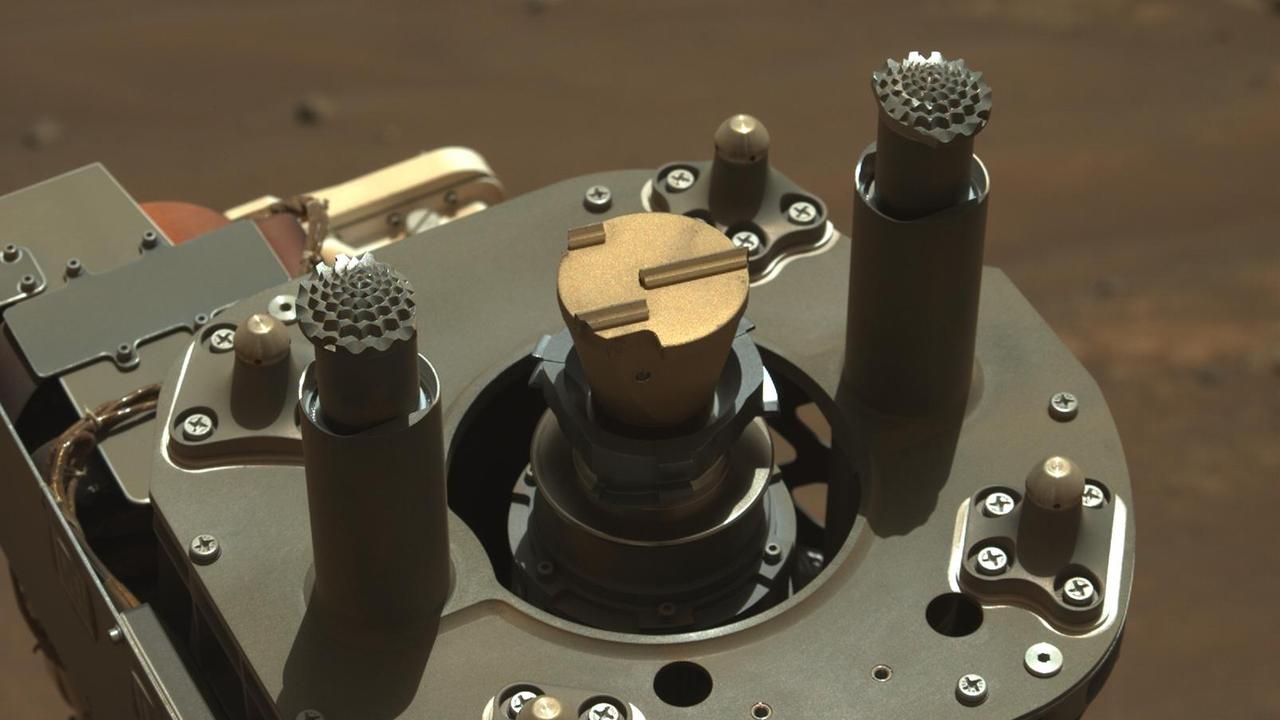 This image shows the abrading bit used by NASA's Perseverance to get beneath the surface of Mars rocks. It was acquired on Aug. 2, 2021, the 160th Martian day, or sol, of the mission, by the rover's Mastcam-Z imager. Mars rocks can be weathered and covered in dust, obscuring important details about their composition and history. The rover's abrader is the golden-colored disk with the three parallel lines of different lengths, arranged asymmetrically, in the center of the image. When the rover's drill spins and hammers with an abrading bit, that tooth pattern creates crisscrossing, well-distributed impacts in the rock. This chips away the surface and makes a smooth, flat patch of fresh rock about 2 inches (5 centimeters) in diameter. https://photojournal.jpl.nasa.gov/catalog/PIA26577