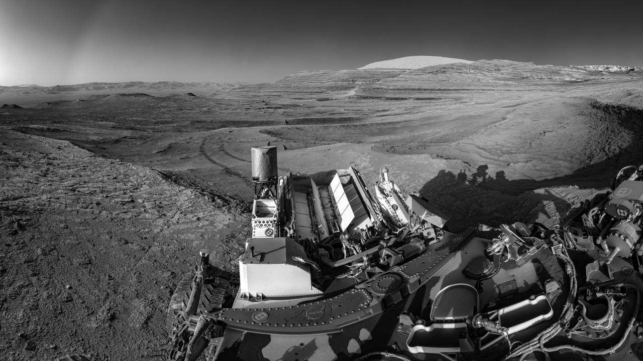 NASA's Curiosity Mars rover demonstrated a new multitasking capability when capturing this view: It snapped the 15 images that make up the mosaic while simultaneously communicating with an orbiter. The images were taken by the right navigation camera on Curiosity's mast July 26, 2025, the 4,611th sol, or day, of the mission. The rover's tracks cross through a region filled with boxwork formations – hardened ridges created by mineral deposits from subsurface water billions of years ago. This boxwork region is in the lower foothills of Mount Sharp, a 3-mile-tall (5-kilometer-tall) mountain in the center of Gale Crater. Being able to combine tasks shortens the rover's daily plan, requiring less power from Curiosity's nuclear power source, called a multi-mission radioisotope thermonuclear generator (MMRTG), which is lined with rows of white fins at the back of the rover. NASA's Perseverance rover is also equipped with an MMRTG; the generator uses the heat from decaying plutonium pellets to charge batteries on the rovers. The can-like cylinder to the left of the MMRTG is Curiosity's ultrahigh frequency (UHF) antenna, which communicates with spacecraft in orbit around Mars. To capture a mosaic like this, the rover would normally require nine minutes of awake time devoted solely to imaging. However, while snapping the images for this mosaic, Curiosity was also sending data to ESA's (the European Space Agency's) Trace Gas Orbiter, essentially saving several minutes of battery time. After being sent to Earth, the images were stitched together and the seams between them smoothed out before the mosaic was processed to enhance details. https://photojournal.jpl.nasa.gov/catalog/PIA26632