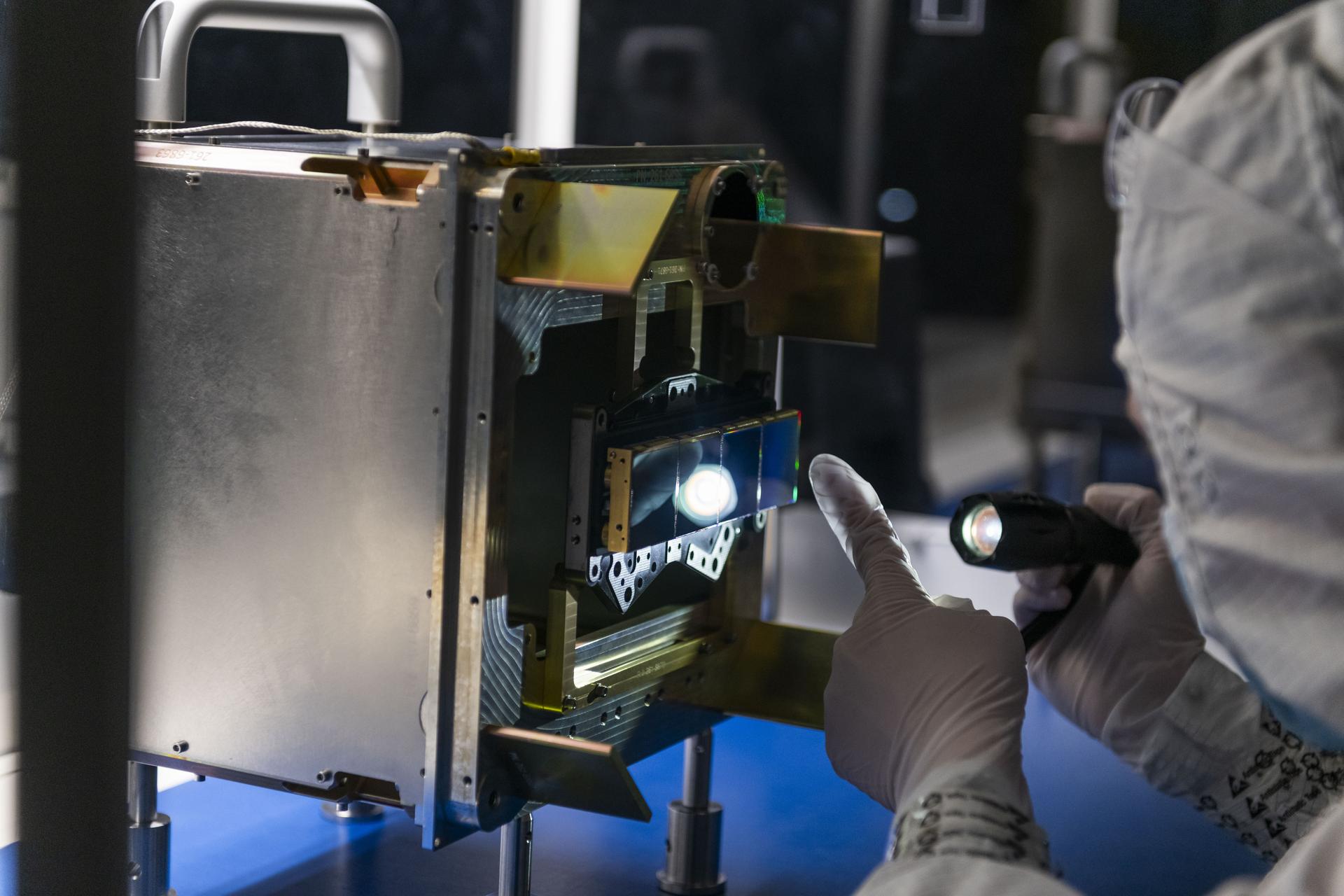 An engineer inspects the surface of four mid-wavelength infrared science detectors for NASA’s Near-Earth Object (NEO) Surveyor mission atop a clean room bench at the Space Dynamics Laboratory (SDL) in Logan, Utah.