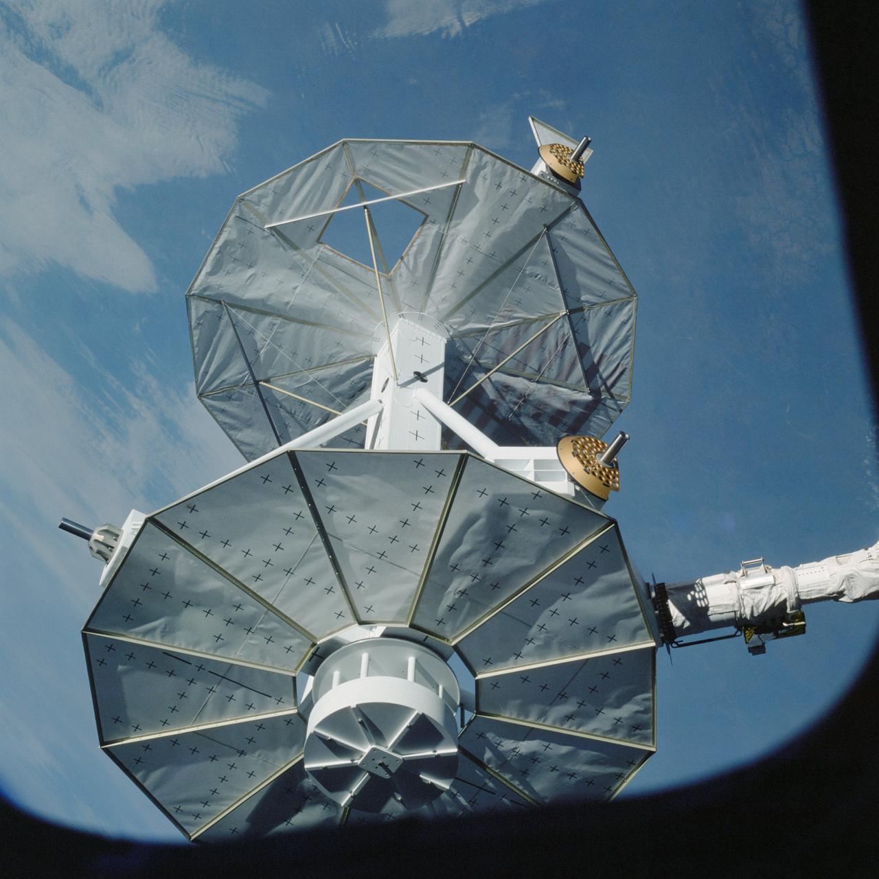 STS008-35-1239 (30 Aug.-5 Sept. 1983) --- The space shuttle Challenger?s payload flight test article (PFTA) is lifted from the cargo bay and held over clouds and water on Earth. The 70mm frame was photographed by one of the five STS-8 crew members with a free hand during the busy RMS/PFTA agenda. Photo credit: NASA