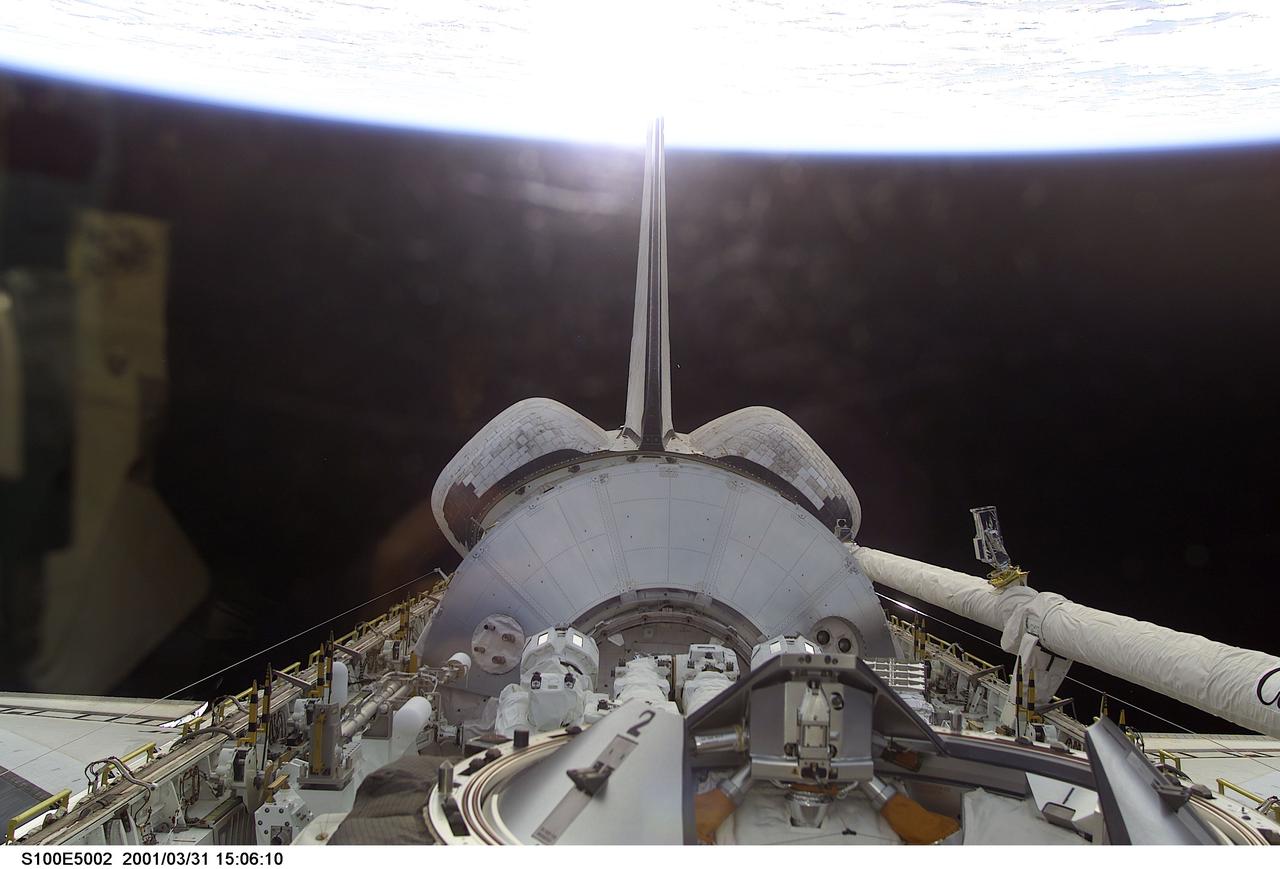 S100-E-5002 (20 April 2001) --- One of the crew members of STS-100 aimed a digital still camera through Endeavour's aft flight deck windows to record this image of the cargo bay, backdropped against a scene of black space and Earth's horizon. Housed in the bay, beyond the docking mechanism in the foreground, is the Italian Space Agency-provided Raffaello cargo module, which is carrying several tons of equipment for the Expedition Two crew and racks of hardware for installation in Destiny which will be used for scientific research in the future. Raffaello, which is the second of three such logistics modules, will be berthed to the ISS on April 23 so its contents can be transferred to the station throughout the course of docked operations. Also in the bay is the 57-foot-long Canadarm2, which will be mounted on the Destiny Laboratory for future station assembly work. Endeavour's Canadian-built Remote Manipulator System (RMS) arm can be seen in its berthed position on the port side of the payload bay.