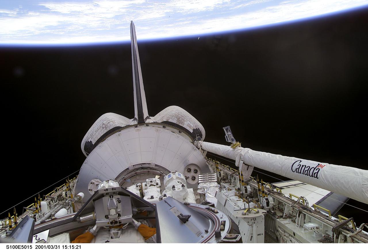 S100-E-5015 (20 April 2001) --- One of the crew members of STS-100 aimed a digital still camera through Endeavour's aft flight deck windows to record this image of the cargo bay, backdropped against a scene of black space and Earth's horizon. Housed in the bay, beyond the docking mechanism in the foreground, is the Italian Space Agency-provided Raffaello cargo module, which is carrying several tons of equipment for the Expedition Two crew and racks of hardware for installation in Destiny which will be used for scientific research in the future. Raffaello, which is the second of three such logistics modules, will be berthed to the ISS on April 23 so its contents can be transferred to the station throughout the course of docked operations. Also in the bay is the 57-foot-long Canadarm2, which will be mounted on the Destiny Laboratory for future station assembly work. Endeavour's Canadian-built Remote Manipulator System (RMS) arm can be seen in its berthed position on the port side of the payload bay.