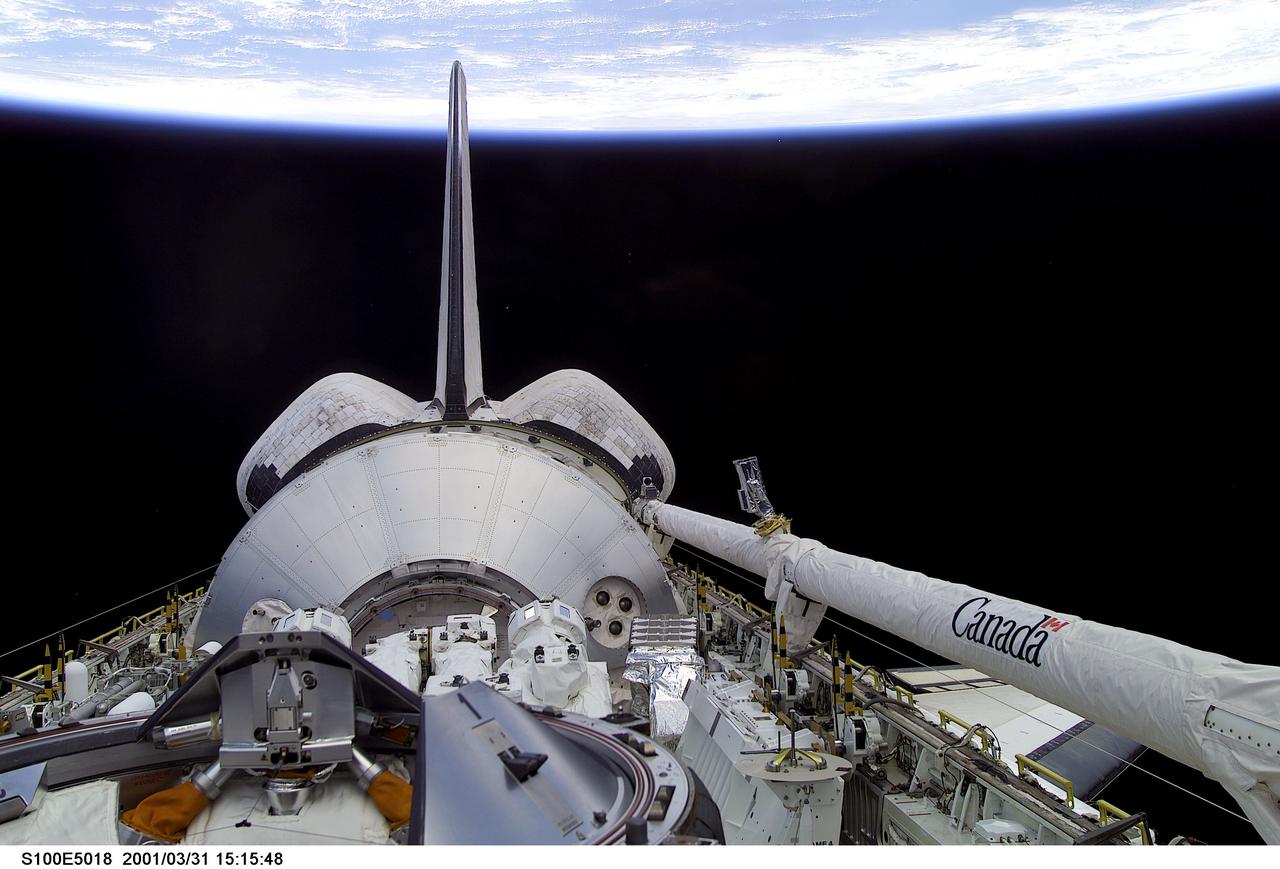 S100-E-5018 (20 April 2001) --- One of the crew members of STS-100 aimed a digital still camera through Endeavour's aft flight deck windows to record this image of the cargo bay, backdropped against a scene of black space and Earth's horizon. Housed in the bay, beyond the docking mechanism in the foreground, is the Italian Space Agency-provided Raffaello cargo module, which is carrying several tons of equipment for the Expedition Two crew and racks of hardware for installation in Destiny which will be used for scientific research in the future. Raffaello, which is the second of three such logistics modules, will be berthed to the ISS on April 23 so its contents can be transferred to the station throughout the course of docked operations. Also in the bay is the 57-foot-long Canadarm2, which will be mounted on the Destiny Laboratory for future station assembly work. Endeavour's Canadian-built Remote Manipulator System (RMS) arm can be seen in its berthed position on the port side of the payload bay.