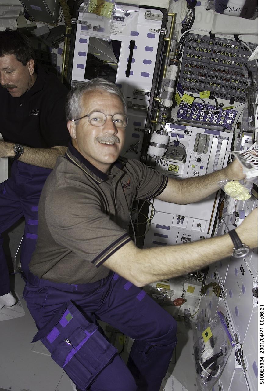 S100-E-5034 (21 April 2001) --- Astronauts Kent V. Rominger (background), STS-100 commander, and John L. Phillips, mission specialist, are seen on the middeck of the Space Shuttle Endeavour as the crew anticipates its union with the International Space Station (ISS). Assigned space-walking astronauts Chris A. Hadfield and Scott E. Parazynski (both out of frame) were later joined on the middeck by spacewalk coordinator Phillips in conducting some final checks of the suits and hardware that were to be used during the next day's planned 6-hour, 30-minute spacewalk. The image was recorded with a digital still camera.