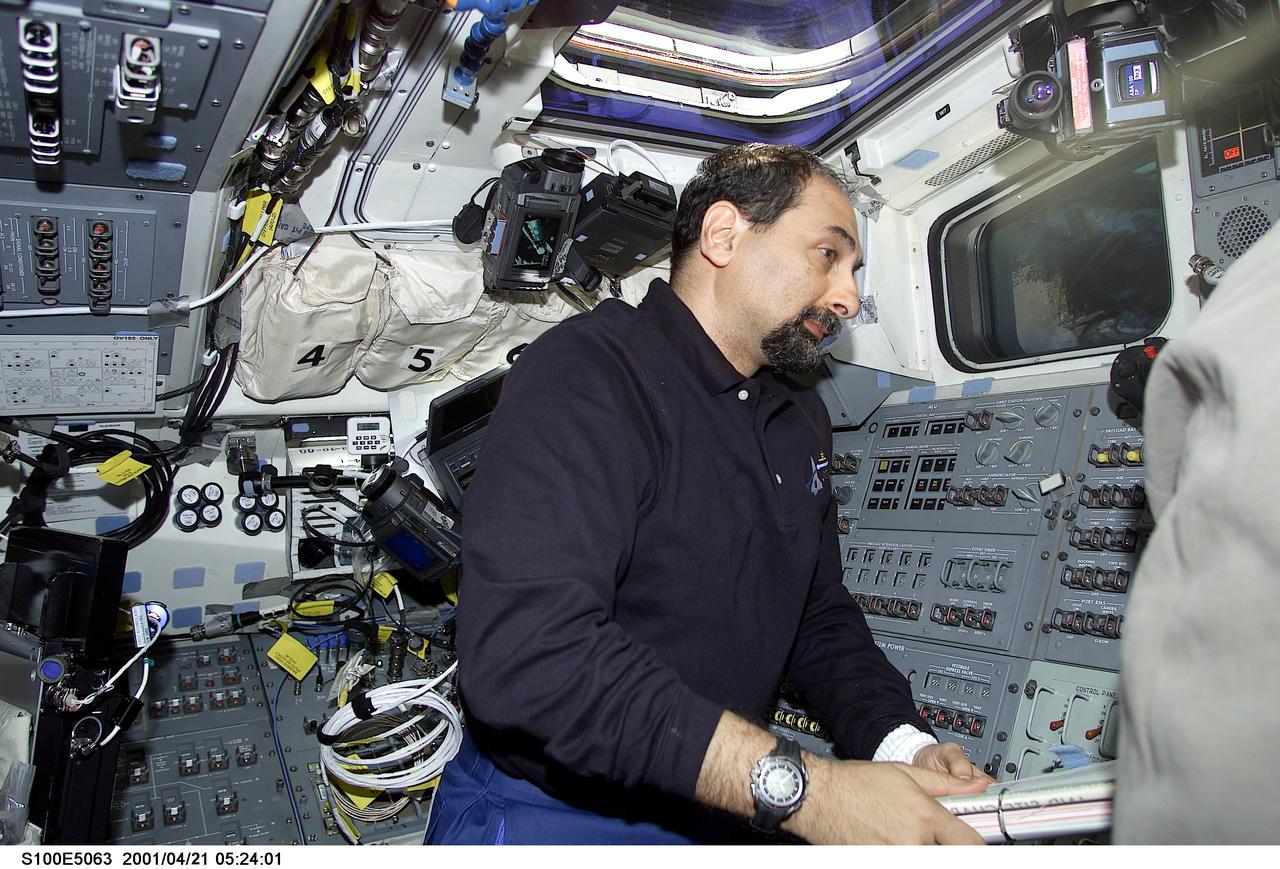 S100-E-5063 (21 April 2001) --- Astronaut Umberto Guidoni, mission specialist representing the European Space Agency (ESA), totes some notebooks of STS-100 mission data on the flight deck of the Earth-orbiting Space Shuttle Endeavour as the seven-member crew heads for a rendezvous with the International Space Station (ISS). The image was recorded with a digital still camera