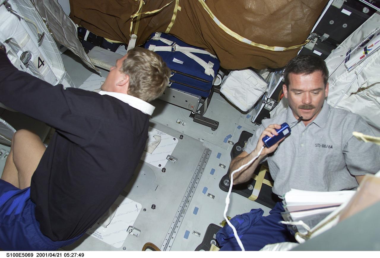 S100-E-5069 (21 April 2001) --- Astronauts Scott E. Parazynski (left) and Canada's Chris A. Hadfield, both mission specialists for STS-100, are pictured on the middeck of the Space Shuttle Endeavour in what is a scene very typical of nearly all the shuttle missions to the International Space Station (ISS). One common denominator of the shuttle-to-station missions is the large load of supplies and equipment transferred from Earth to the outpost, as well as the necessary inventory tasks that accompany the gear. This image was recorded by a fellow crew member using a digital still camera.