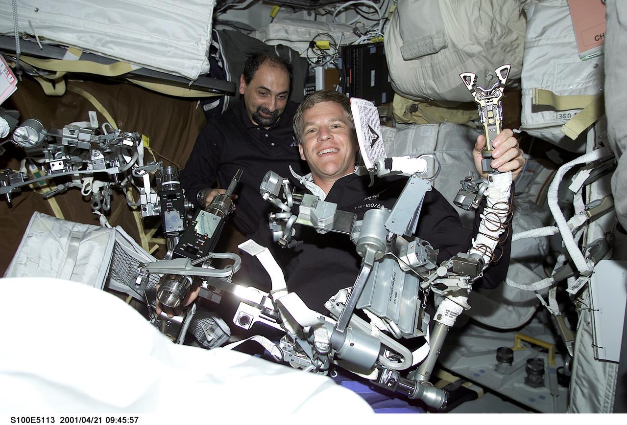 S100-E-5113 (21 April 2001) --- Astronaut Scott E. Parazynski, one of two astronauts assigned to scheduled extravehicular activity (EVA) with the International Space Station (ISS), checks over EVA-related equipment on the middeck of the Space Shuttle Endeavour as the seven-member STS-100 crew busily prepares for its fastly-approaching rendezvous with the orbiting outpost. Astronaut Umberto Guidoni, mission specialist representing the European Space Agency, helps out. The image was recorded with a digital still camera.