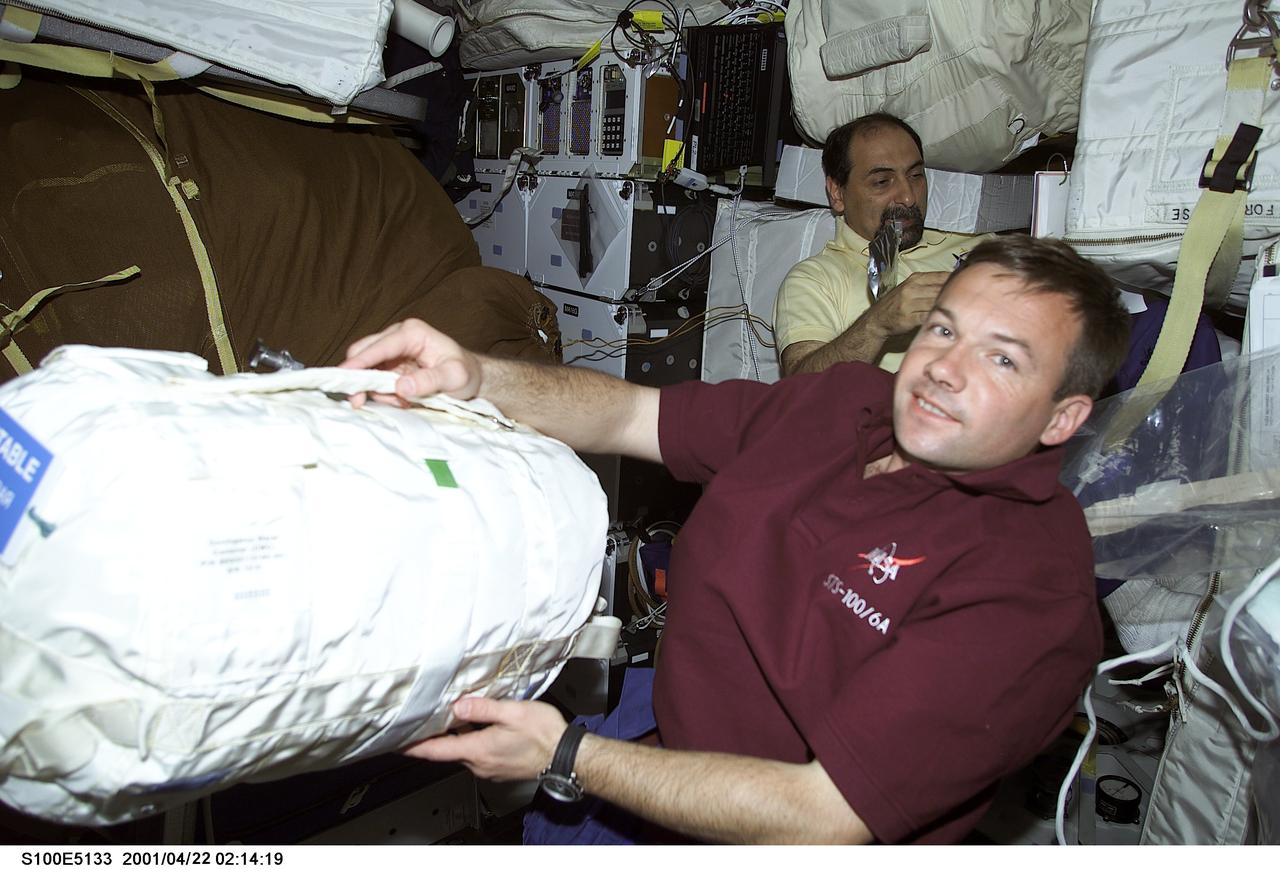 S100-E-5133 (21 April 2001) --- Cosmonaut Yuri V. Lonchakov of Rosaviakosmos shifts the stowage location of water brought up from Earth for use on the International Space Station (ISS). Astronaut Umberto Guidoni of the European Space Agency (ESA) is in the background. The middeck scene was photographed with a digital still camera.