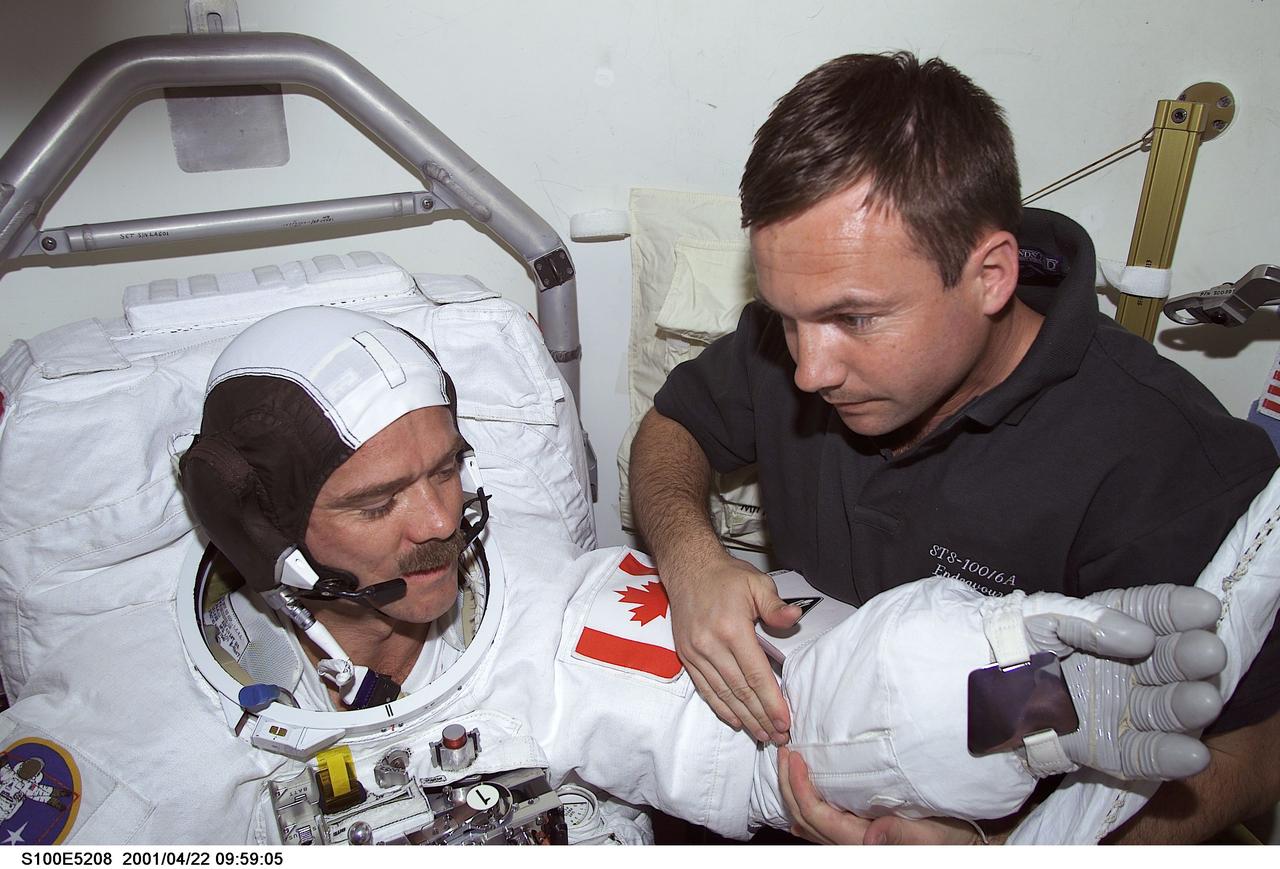S100-E-5208 (22 April 2001) --- Cosmonaut Yuri V. Lonchakov (right), STS-100 mission specialist representing Rosaviakosmos, assists astronaut Chris A. Hadfield, mission specialist representing the Canadian Space Agency (CSA), as he dons his extravehicular mobility unit (EMU) spacesuit onboard the Space Shuttle Endeavour. Hadfield was about to join astronaut Scott E. Parazynski (out of frame), mission specialist, in a scheduled spacewalk to accomplish important work on the International Space Station (ISS), to which the shuttle will be docked for several days.  The image was recorded with a digital still camera.