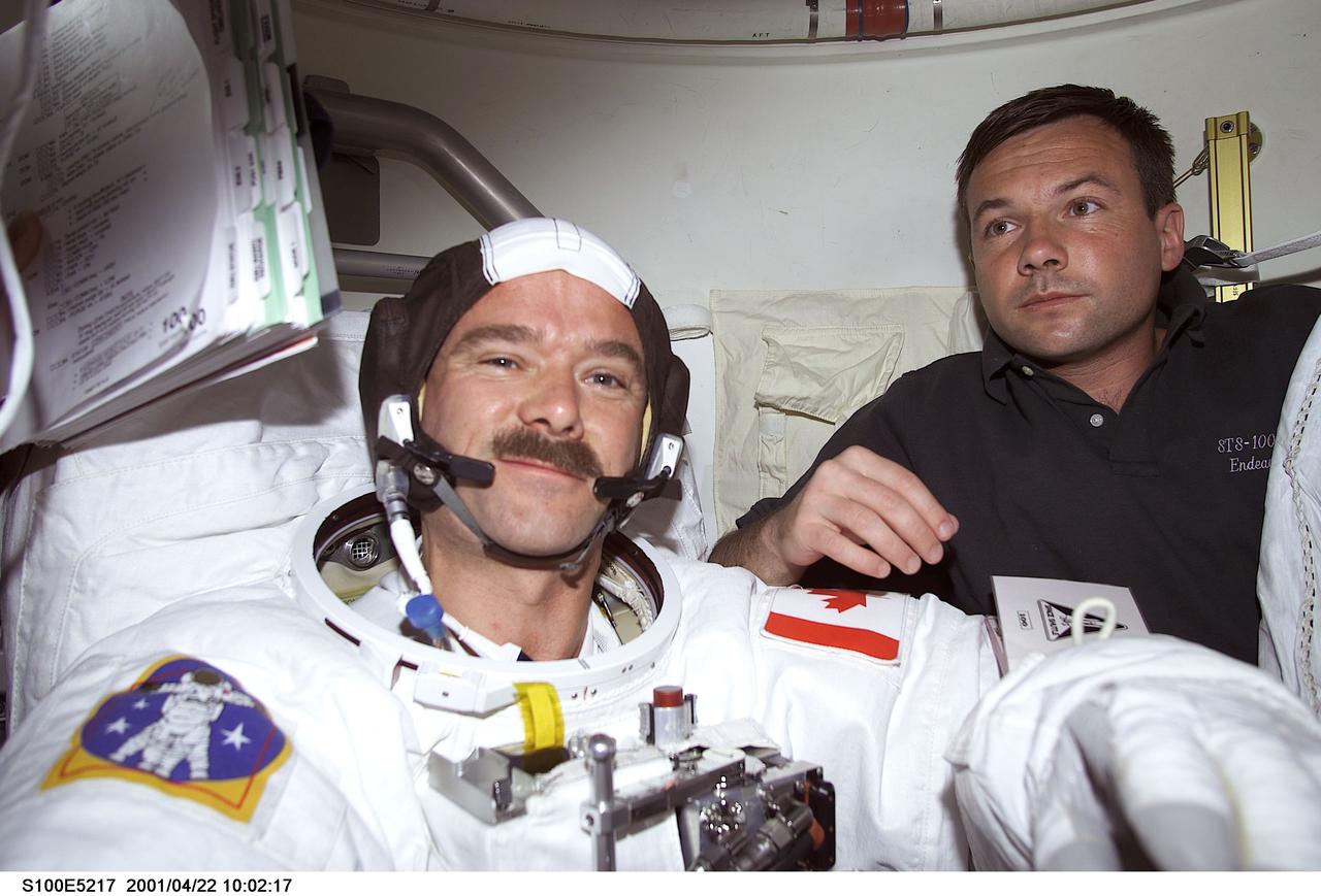 S100-E-5217 (22 April 2001) --- Cosmonaut Yuri V. Lonchakov (right), STS-100 mission specialist representing Rosaviakosmos, assists astronaut Chris A. Hadfield, mission specialist representing the Canadian Space Agency (CSA), as he dons his Extravehicular Mobility Unit (EMU) spacesuit onboard the Space Shuttle Endeavour. Hadfield was about to join astronaut Scott E. Parazynski (out of frame), mission specialist, in a scheduled spacewalk to accomplish important work on the International Space Station (ISS), to which the shuttle will be docked for several days.  The image was recorded with a digital still camera.