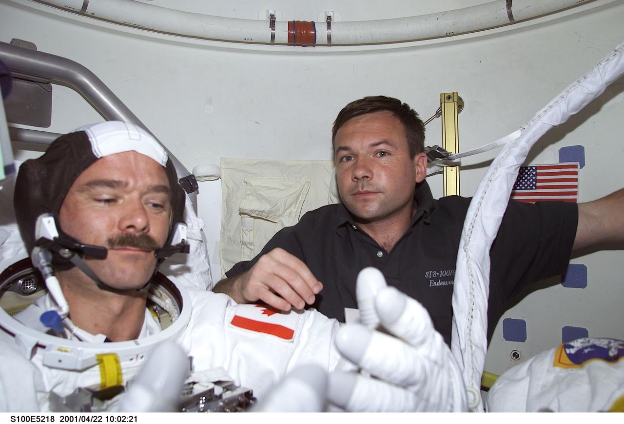 S100-E-5218 (22 April 2001) --- Cosmonaut Yuri V. Lonchakov (right), STS-100 mission specialist representing Rosaviakosmos, assists astronaut Chris A. Hadfield, mission specialist representing the Canadian Space Agency (CSA), as he dons his Extravehicular Mobility Unit (EMU) spacesuit onboard the Space Shuttle Endeavour. Hadfield was about to join astronaut Scott E. Parazynski (out of frame), mission specialist, in a scheduled spacewalk to accomplish important work on the International Space Station (ISS), to which the shuttle will be docked for several days.  The image was recorded with a digital still camera.