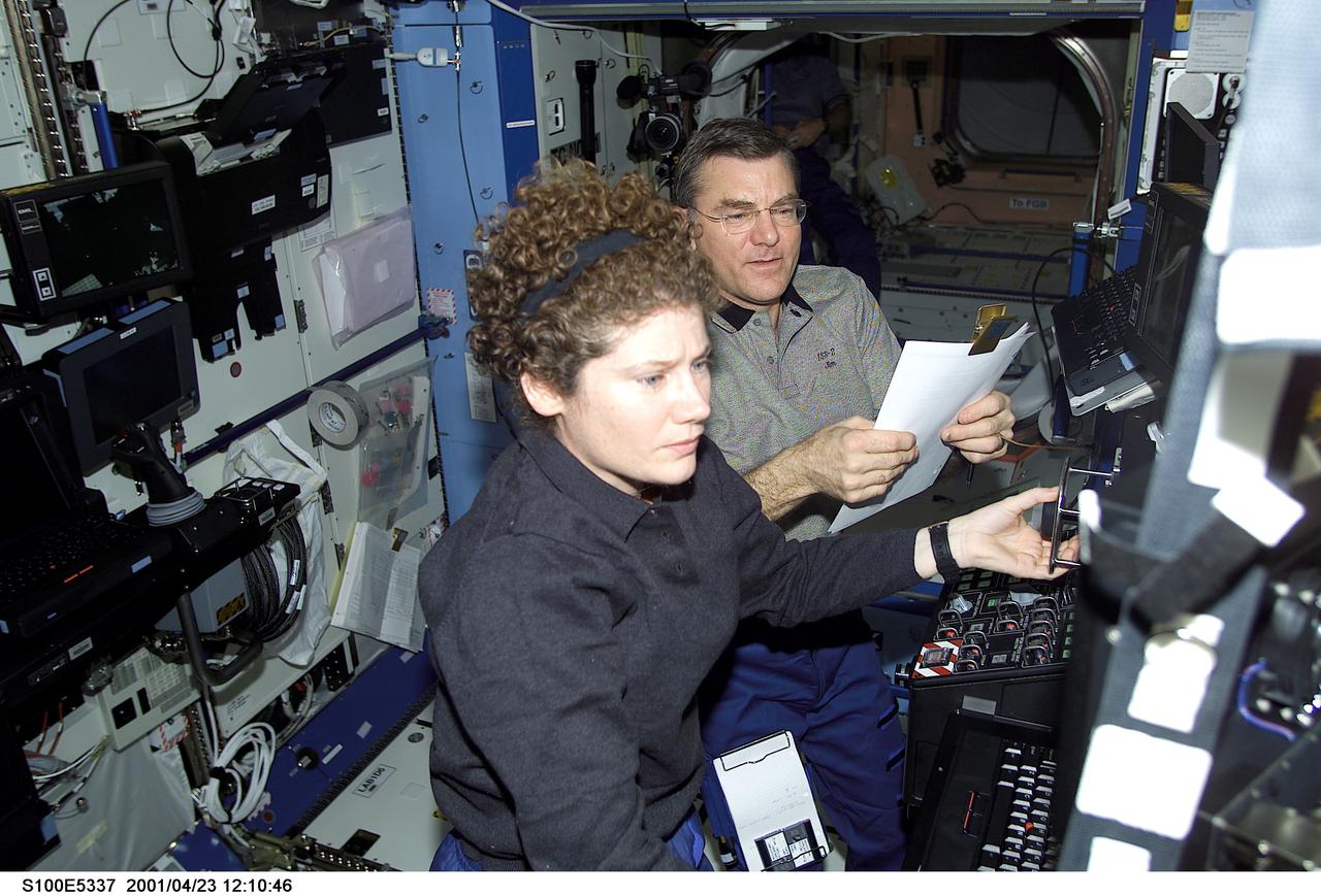 S100-E-5337 (23 April 2001) --- Astronauts Susan J. Helms and James S. Voss, Expedition Two flight engineers,work together to check out some data in the Destiny laboratory aboard the International Space Station (ISS). The image was recorded witha digital still camera by one of the visiting STS-100 crew members.
