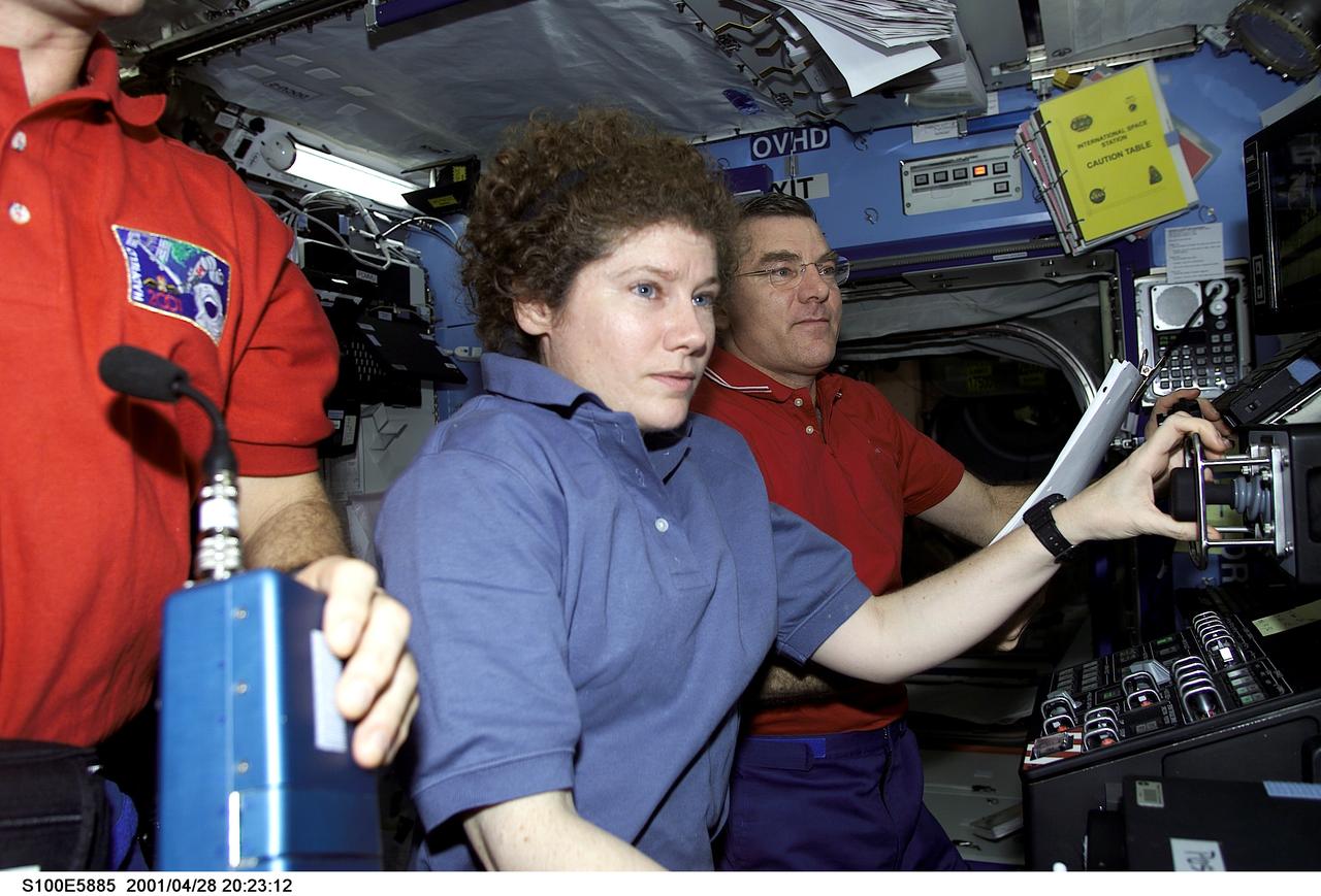 S100-E-5885 (28 April 2001) --- Some of the principal participants of an historical event are pictured in the Destiny laboratory aboard the International Space Station (ISS). From left to right are astronauts Chris A. Hadfield (partially out of frame), STS-100 mission specialist, and astronauts Susan J. Helms and James S. Voss, Expedition Two flight engineers. A Canadian “handshake in space” occurred at 4:02 p.m (CDT), April 28, 2001, as the Canadian-built space station robotic arm – operated by Helms – transferred its launch cradle over to Endeavour’s robotic arm, with Canadian Space Agency astronaut Hadfield at the controls. In this scene, Hadfield has temporarily vacated his post on Endeavour's aft flight deck and was having a brief strategy meeting with the Expedition Two crew on the docked station. The exchange of the pallet from station arm to shuttle arm marked the first ever robotic-to-robotic transfer in space. This image was recorded with a digital still camera.