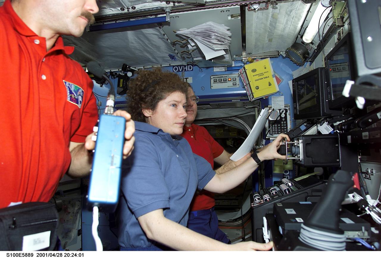 S100-E-5889 (28 April 2001) --- Two of the principal participants of an historical event are pictured in the Destiny laboratory aboard the International Space Station (ISS). Pictured are astronauts Chris A. Hadfield (partially out of frame), STS-100 mission specialist, and astronaut Susan J. Helms, flight engineer for Expedition Two. Astronaut James S. Voss, Expedition Two flight engineer, is in the background. A Canadian “handshake in space” occurred at 4:02 p.m (CDT), April 28, 2001, as the Canadian-built space station robotic arm – operated by Helms – transferred its launch cradle over to Endeavour’s robotic arm, with Canadian Space Agency astronaut Hadfield at the controls. In this scene, Hadfield has temporarily vacated his post on Endeavour's aft flight deck and was having a brief strategy meeting with Helms on the docked station. The exchange of the pallet from station arm to shuttle arm marked the first ever robotic-to-robotic transfer in space. This image was recorded with a digital still camera.