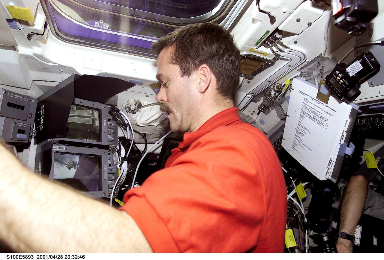 S100-E-5893 (28 April 2001) --- Astronaut Chris A. Hadfield, mission specialist, is pictured on the aft flight deck of the Space Shuttle Endeavour during an historic event. A Canadian “handshake in space” occurred at 4:02 p.m (CDT), April 28, 2001, as the Canadian-built space station robotic arm – operated by Expedition Two flight engineer Susan Helms – transferred its launch cradle over to Endeavour’s robotic arm, with Canadian Space Agency astronaut Hadfield at the controls. The exchange of the pallet from station arm to shuttle arm marked the first ever robotic-to-robotic transfer in space. This image was recorded with a digital still camera.