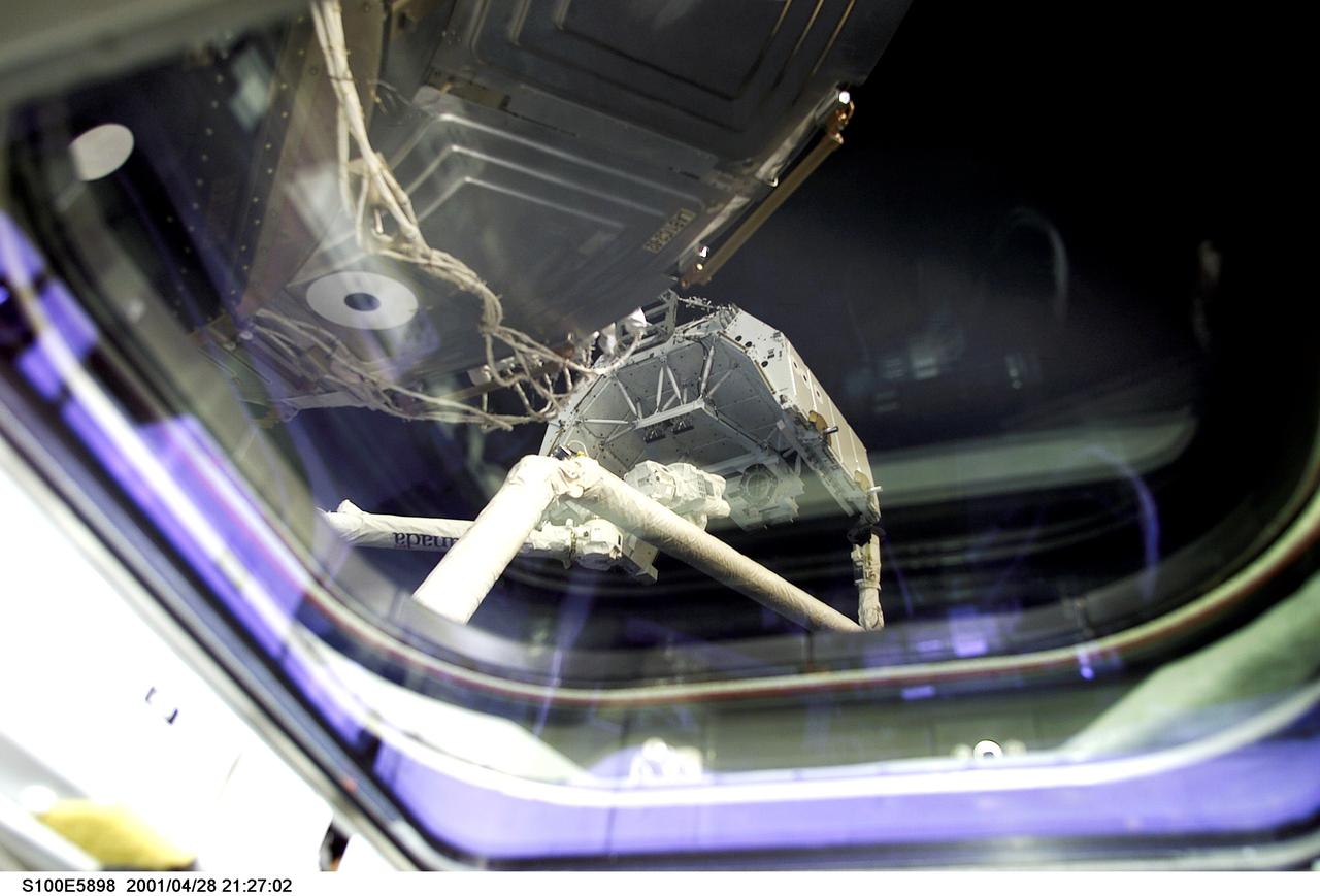 S100-E-5898 (28 April 2001) --- A STS-100 crew member with a digital still camera recorded this image of an historical event through an overhead window on the aft flight deck of the Space Shuttle Endeavour.  A Canadian “handshake in space” occurred at 4:02 p.m (CDT), April 28, 2001, as the Canadian-built space station robotic arm – operated by Expedition Two flight engineer Susan J. Helms –transferred its launch cradle over to Endeavour’s robotic arm, with   Canadian Space Agency astronaut Chris A. Hadfield at the controls. The exchange of the pallet from station arm to shuttle arm marked the first ever robotic-to-robotic transfer in space.