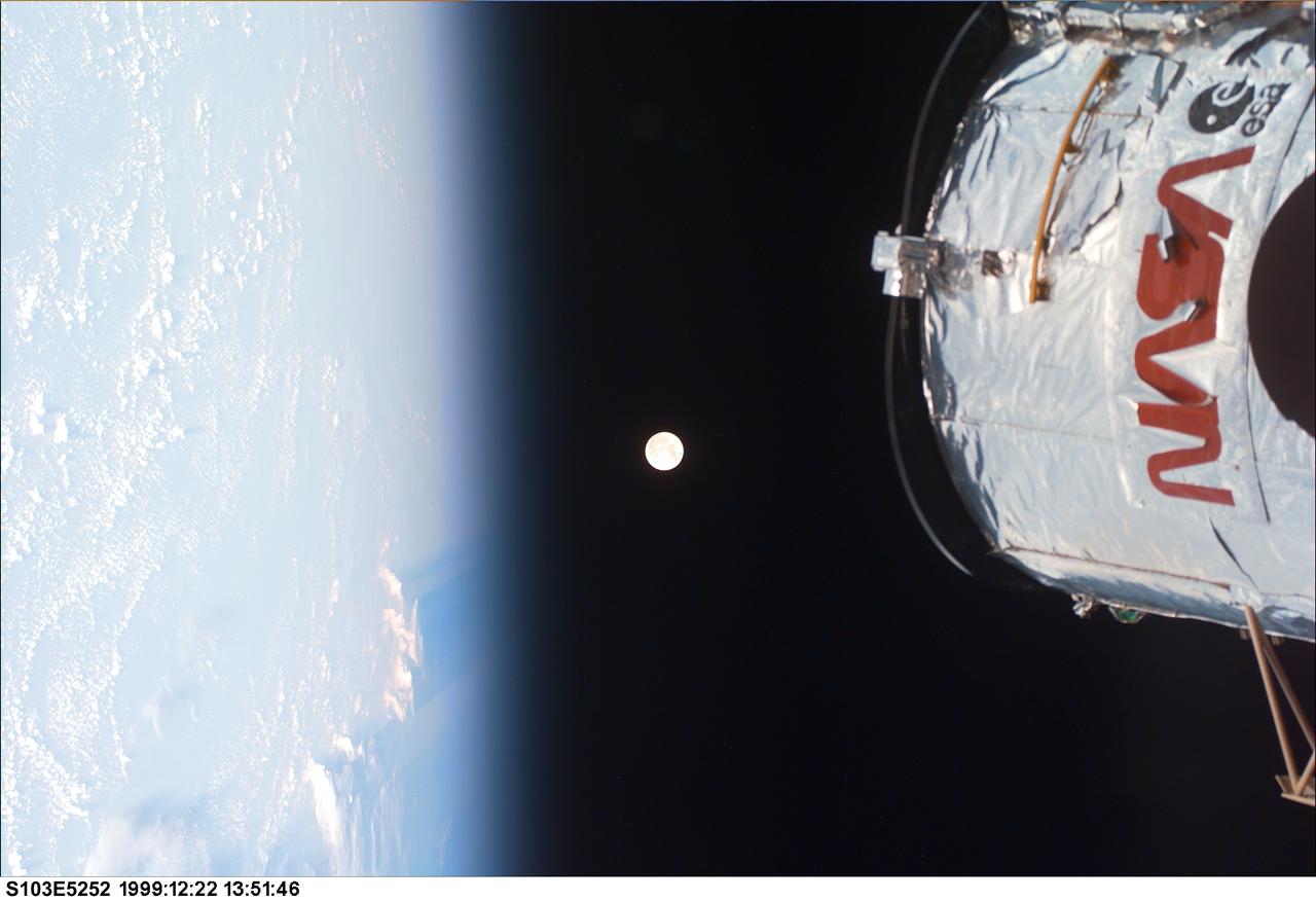 S103-E-5252 (22 December 1999) --- One of the STS-103 astronauts inside Discovery's cabin took this electronic still camera's (ESC) image of a full moon backdropped against the blackness of space over Earth's horizon.  The top of the captured Hubble Space Telescope (HST) appears in the frame.