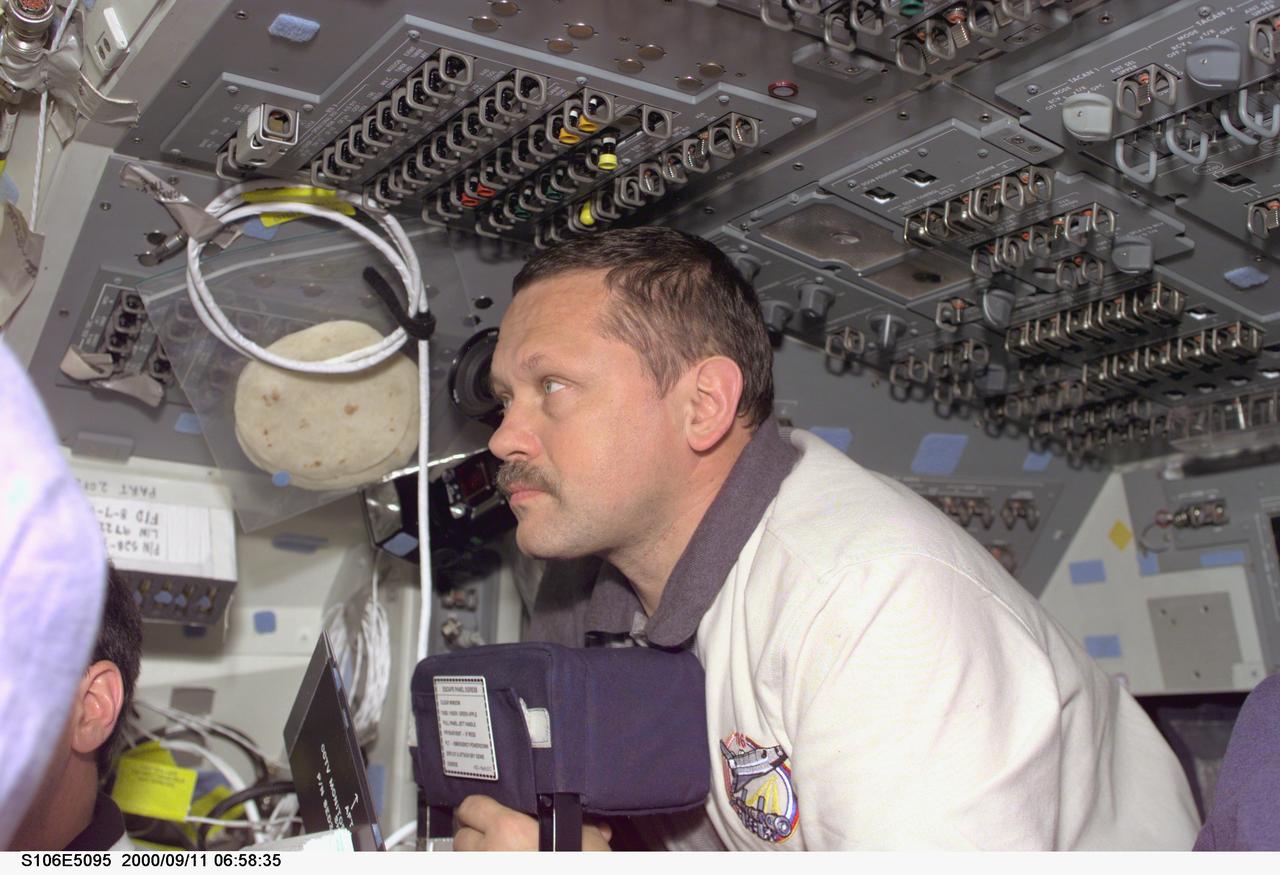S106-E-5095 (11 September 2000) --- Cosmonaut Boris V. Morukov, mission specialist representing the Russian Aviation and Space Agency, is attentive to a crew head session on the flight deck of the Earth-orbiting Space Shuttle Atlantis. The Atlantis was docked with the International Space Station (ISS) when this electronic still camera's (ESC) image was recorded.