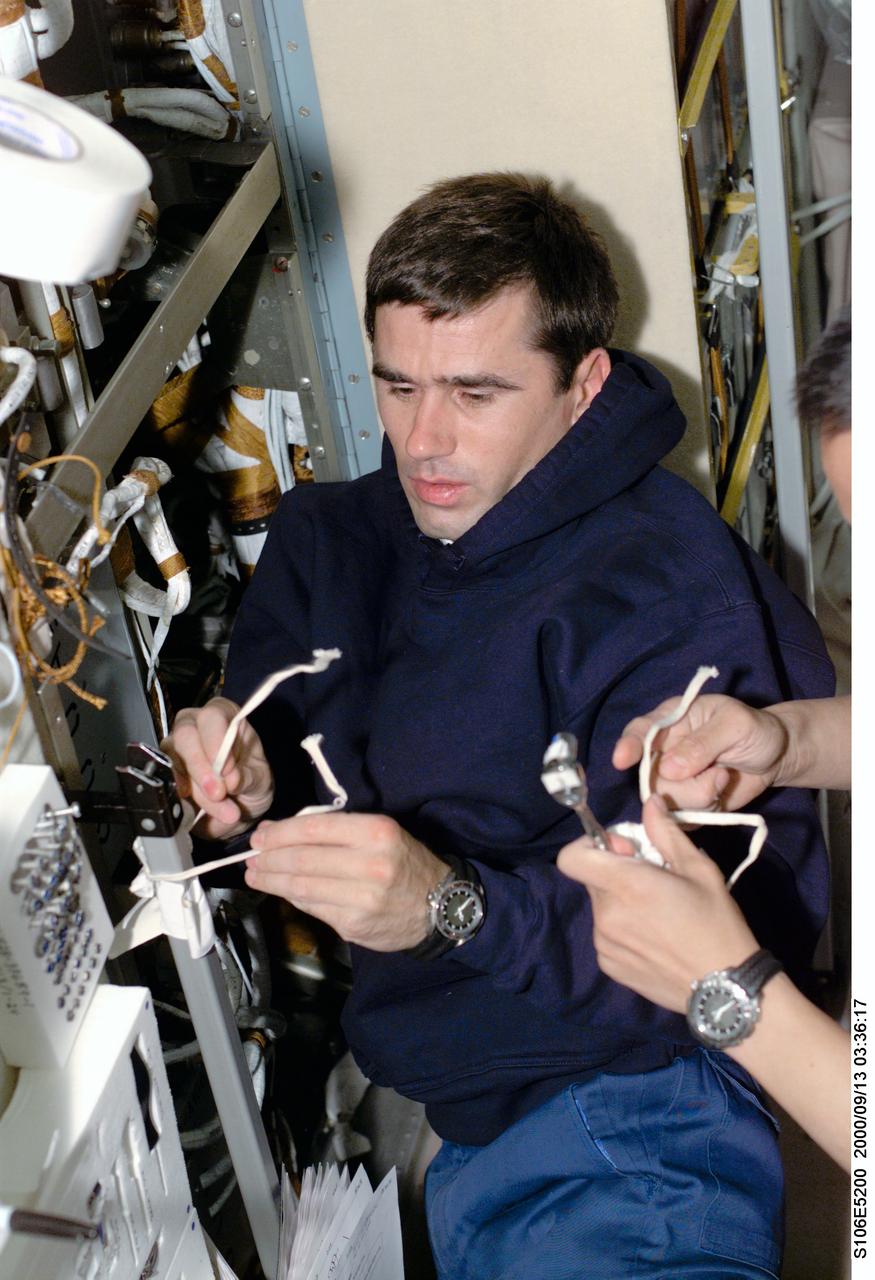 S106-E-5200 (13 September 2000) --- Cosmonaut Yuri I. Malenchenko, mission specialist representing the Russian Aviation and Space Agency, works aboard the Zvezda service module on the International Space Station (ISS).  Electrical work was the hallmark of this day as four of the mission specialists aboard ISS (temporarily docked with the Space Shuttle Atlantis) replaced batteries inside the Zarya and Zvezda modules while supply transfer continued around them. Astronaut Edward T. Lu, mission specialist, is out of frame at right.