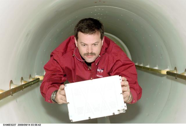 NASA image: Pilot Altman carries a battery through the transfer tunnel during STS-106