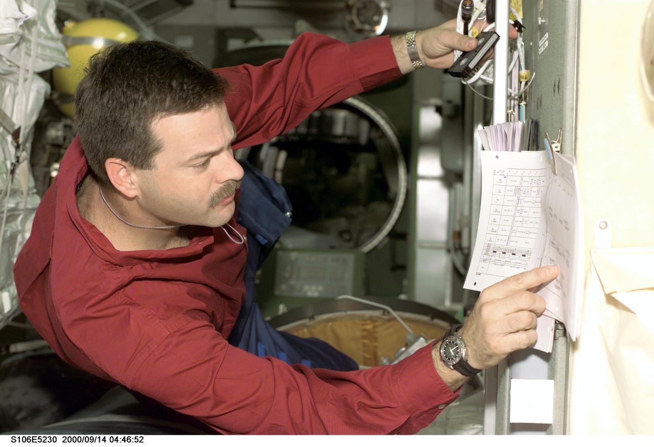S106-E-5230 (14 September 2000) --- Astronaut Scott D. Altman, pilot, checks the crew activity timeline posted on the wall of the Zvezda service module during   Flight Day 6 activity.