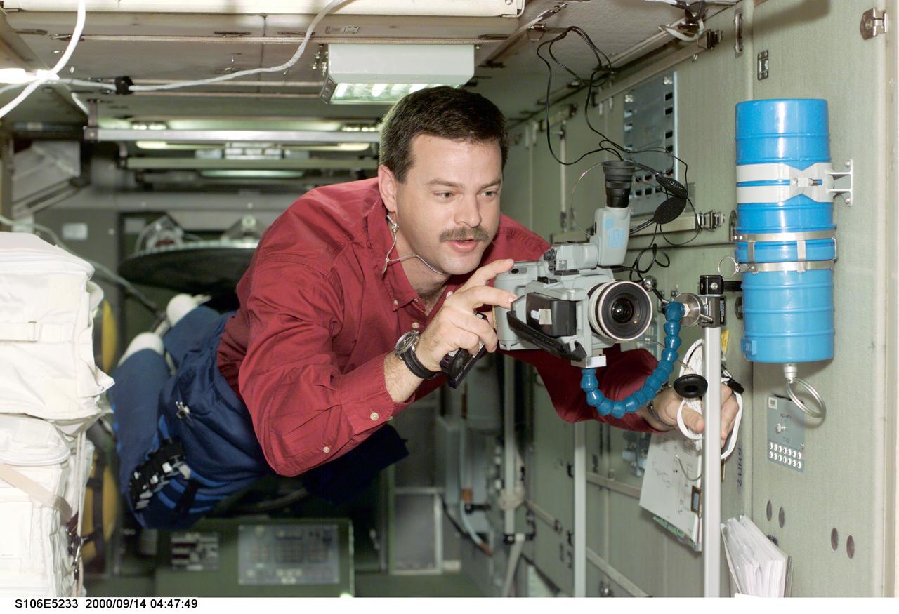S106-E-5233 (14 September 2000) --- Astronaut Scott D. Altman, pilot, sets up a camcorder in the Zvezda service module during late Flight Day 6 activity.