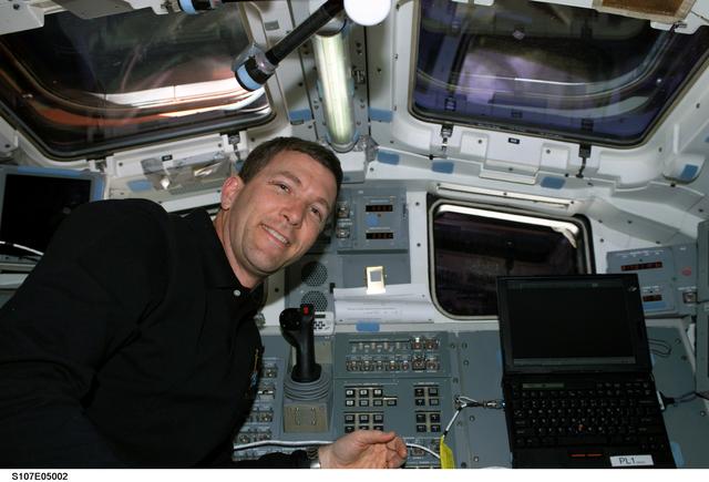 NASA image: Husband smiles for the camera beside Columbia's AFD control panel during STS-107