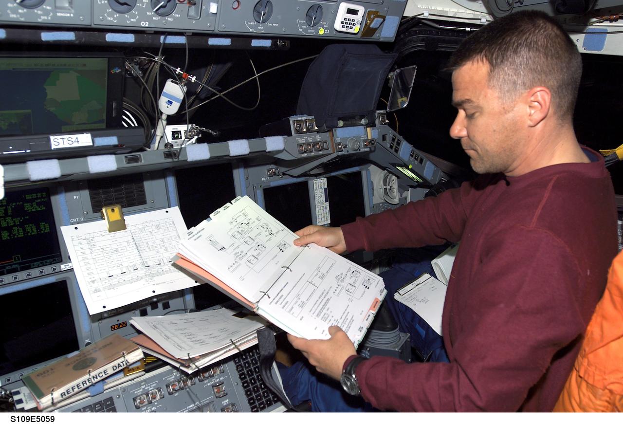 STS109-E-5059 (3 March 2002)  ---  Astronaut Duane G. Carey, STS-109 pilot, looks over a reference manual during capture and latch operations with the Hubble Space Telescope.  The image was recorded with a digital still camera.
