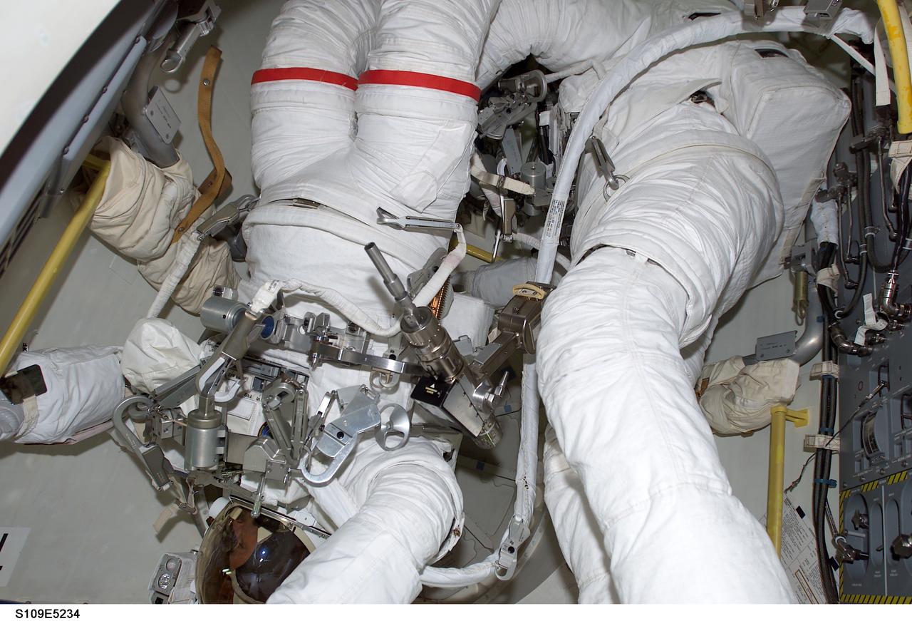 STS109-E-5234 (4 March 2002) --- Astronauts John M. Grunsfeld (left), payload commander, and Richard M. (Rick) Linnehan, mission specialist, are just moments away from going from a crowded situation into a more spacious venue as they prepare to egress the airlock of the Space Shuttle Columbia for the first of their assigned STS-109 space walks to perform work on the Hubble Space Telescope (HST).The two went on to replace the giant telescope’s starboard solar array during a space walk that ended at 7:38 a.m. (CST) or 13:38 GMT March 4, 2002.