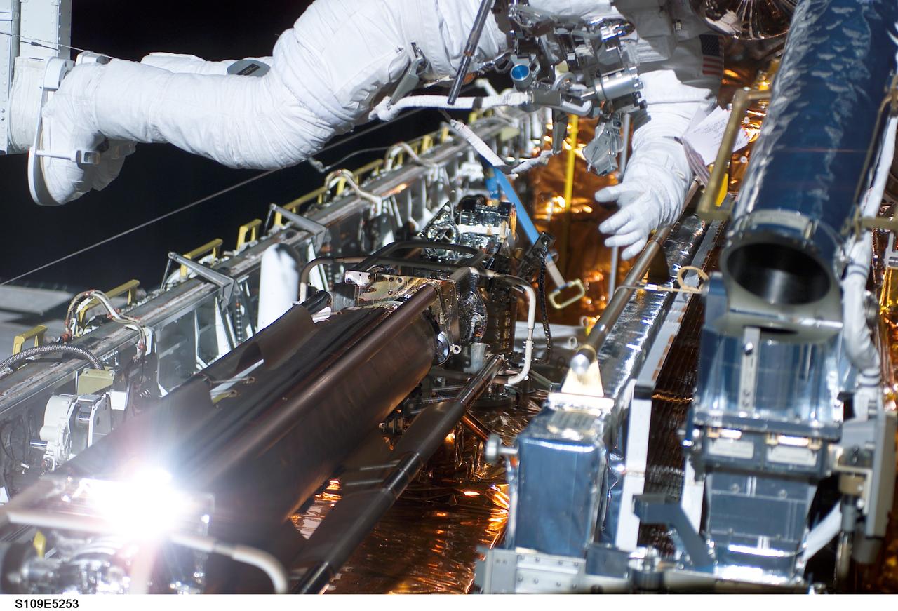 STS109-E-5253 (4 March 2002) --- Astronaut Richard M. Linnehan, mission specialist, is about to wrap up the first phase of a seven-hour space walk in the cargo bay of the Space Shuttle Columbia. Linnehan's feet are anchored to a restraint on the end of the Remote Manipulator System (RMS) robotic arm. The piece of hardware putting on a bright glow in left foreground is the furled old solar array that astronauts Linnehan and John M. Grunsfeld, payload commander, earlier removed from Hubble Space Telescope. The old array is now latched in Columbia's cargo bay for return to Earth. The two went on to install the replacement starboard array. The image was recorded with a digital still camera.