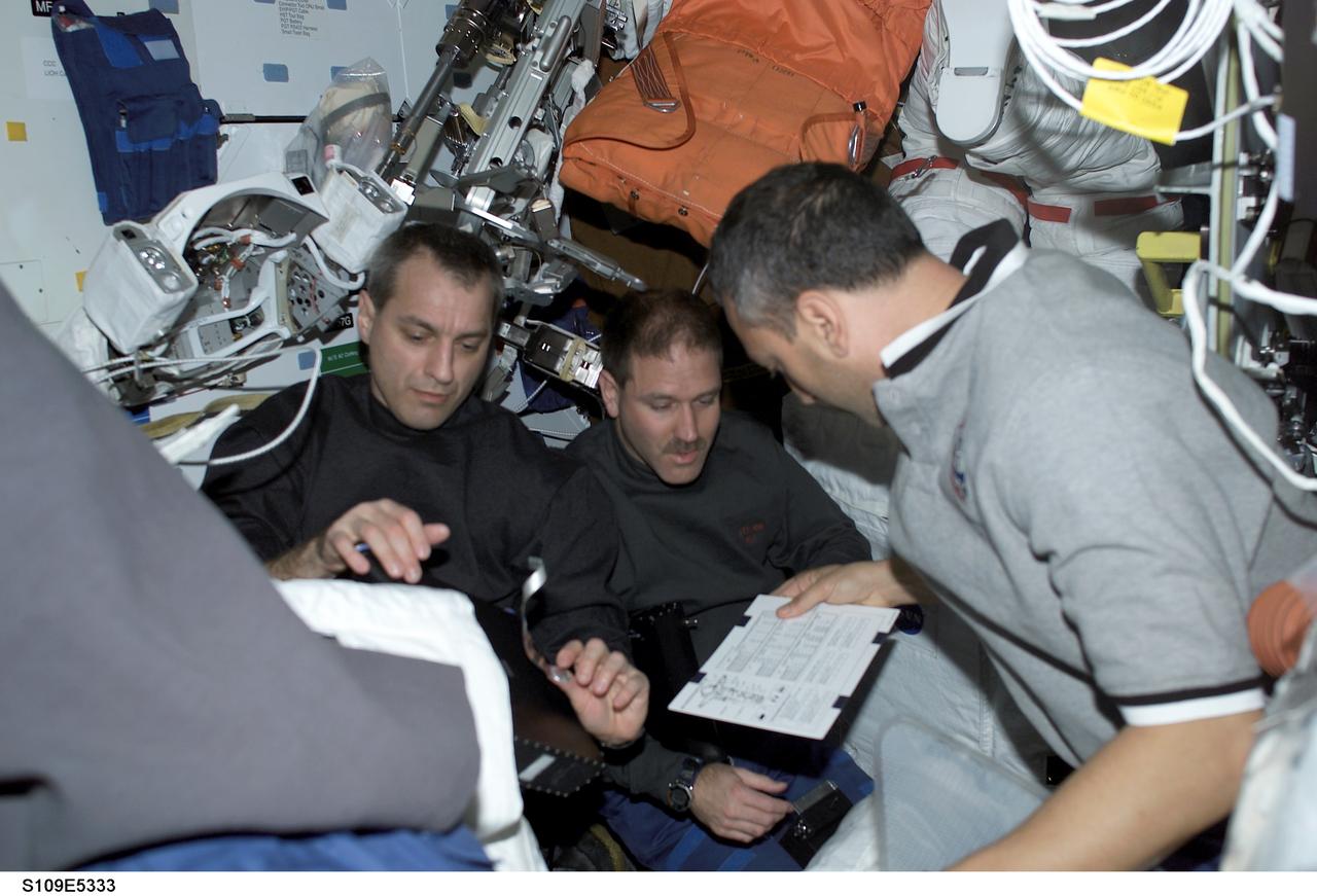 STS109-E-5333 (4 March 2002) --- Three STS-109 crew members assigned to extravehicular activity (EVA) duty on the Hubble Space Telescope (HST) discuss strategy on the mid deck of the Space Shuttle Columbia. From the left are astronauts Richard M. Linnehan, John M. Grunsfeld and Michael J. Massimino. The image was recorded with a digital still camera.