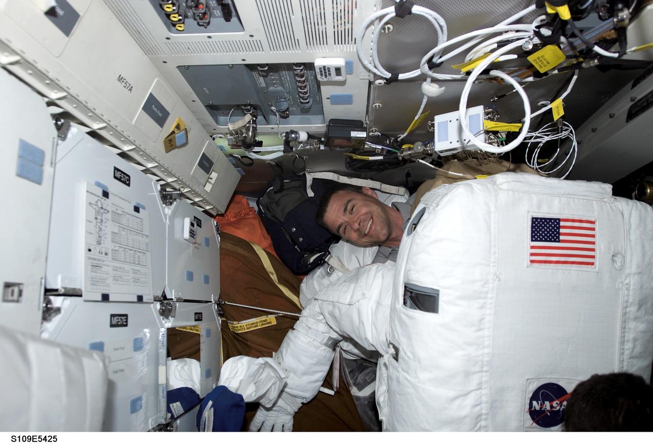 STS109-E-5425 (7 March 2002) ---  On the mid deck of the Space Shuttle Columbia, astronaut Duane G. Carey, STS-109 pilot, works with the extravehicular mobility unit (EMU) space suit of one of his crewmates. Astronauts James H. Newman and Michael J. Massimino, mission specialists, were about to begin the fourth space walk of the mission to perform several tasks on the Hubble Space Telescope (HST). The image was recorded with a digital still camera.