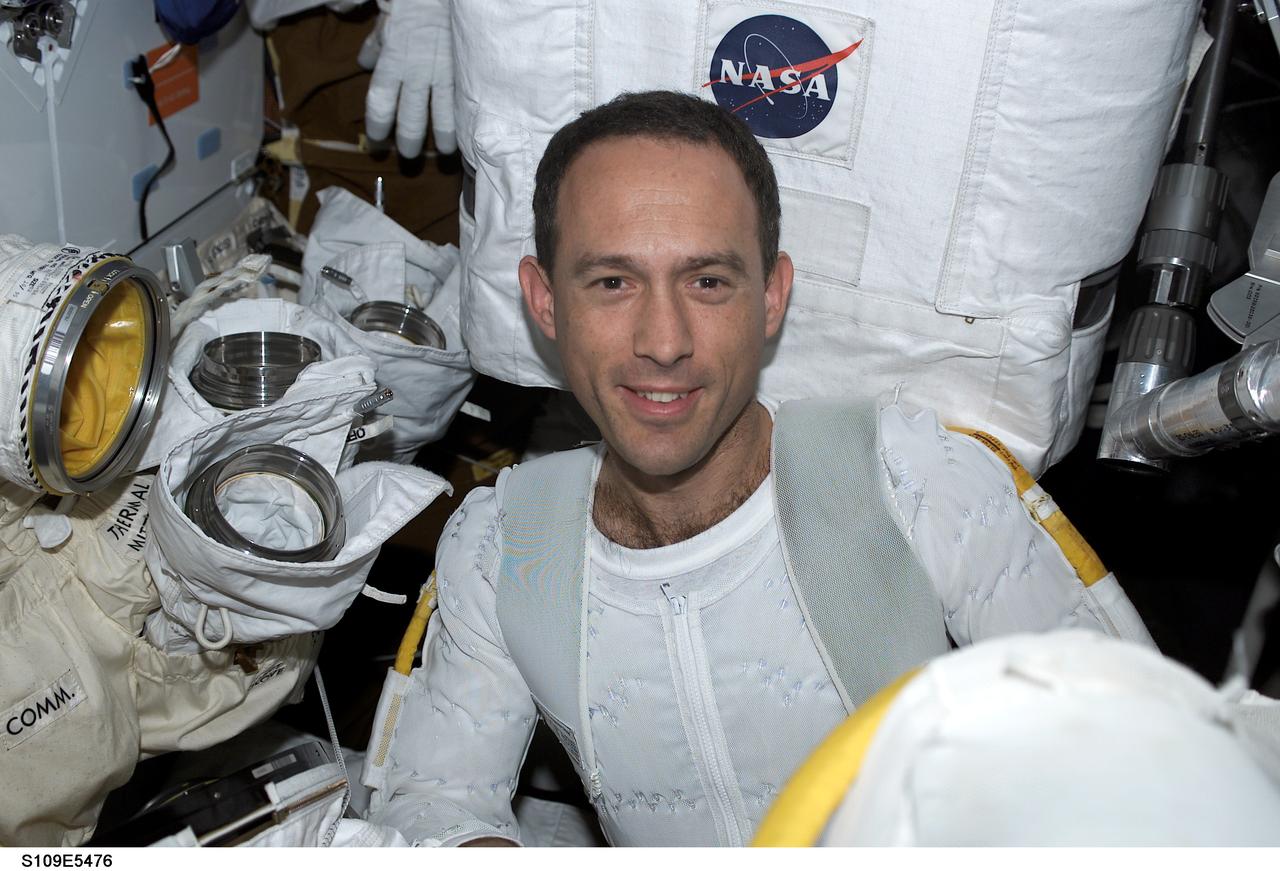 STS109-E-5476 (7 March 2002)-- Astronaut James H. Newman prepares to don his extravehicular mobility unit (EMU) space suit in order to participate in the fourth of five scheduled STS-109 space walks to work on the Hubble Space Telescope (HST).  This image was recorded with a digital still camera.