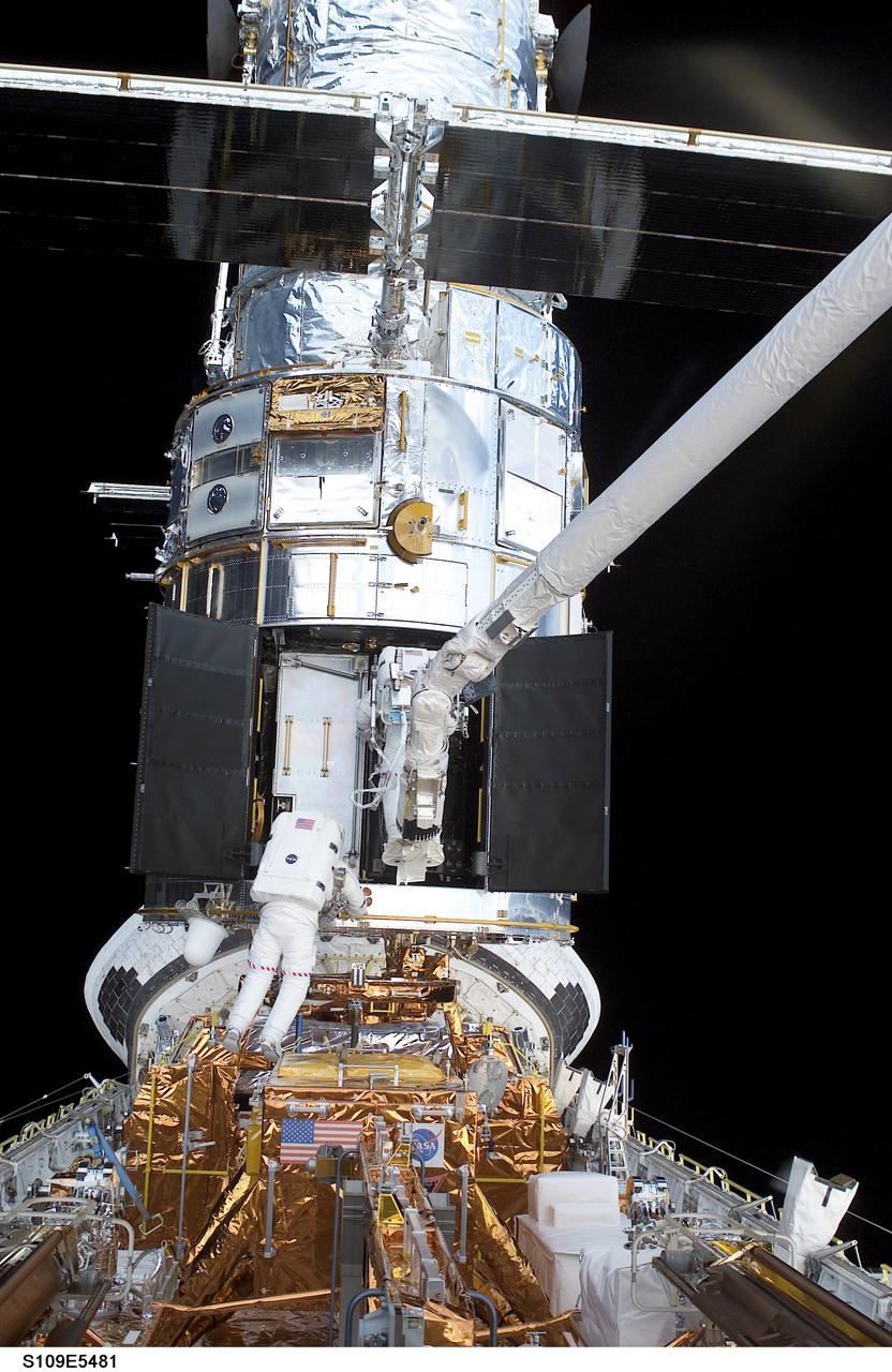STS109-E-5481 (7 March 2002) --- Two of Columbia's four spacewalkers--astronauts James H. Newman and Michael J. Massimino--participate in the first science instrument upgrade of the fourth Hubble Space Telescope (HST) servicing mission during the flight's fourth day of extravehicular activity (EVA). The two, with Newman on Columbia's remote manipulator system (RMS) robotic arm,  removed the Faint Object Camera to make room for the new Advanced Camera for Surveys (ACS). This image was recorded with a digital still camera by one of the duo's crewmates on the aft flight deck.