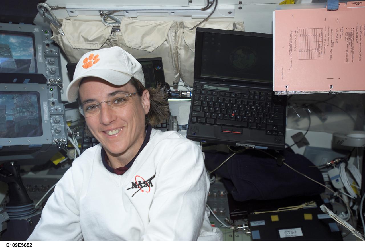 STS109-E-5682 (7 March 2002) --- Astronaut Nancy J. Currie, mission specialist, remains very near the controls for Columbia's Remote Manipulator System (out of frame) on the crew cabin's aft flight deck.  On a week with one lengthy space walk per day, Currie has had her hands full with   RMS duties to support the space walks of four crewmates.  A short time later on this day, astronauts James H. Newman and  Michael J. Massimino began EVA-4, during which the duo required the services of Currie to control the robotic arm to maneuver them around the various work stations on the Hubble Space Telescope (HST).  The image was recorded with a digital still camera.