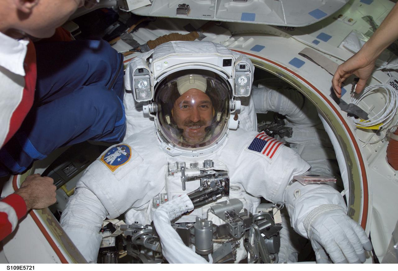 STS109-E-5721 (8 March 2002) --- Astronaut John M. Grunsfeld, STS-109 payload commander, attired in the extravehicular mobility unit (EMU) space suit, completed suited is in the Space Shuttle Columbia’s airlock. Grunsfeld and Richard M. Linnehan, mission specialist, were about to participate in STS-109’s fifth space walk. Activities for EVA-5 centered around the Near-Infrared Camera and Multi-Object Spectrometer (NICMOS) to install a Cryogenic Cooler and its Cooling System Radiator. The image was recorded with a digital still camera.