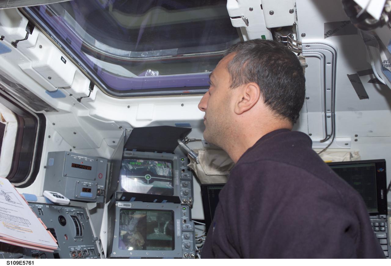 STS109-E-5761 (9 March 2002) --- Astronaut Michael J. Massimino, STS-109 mission specialist, looks through an overhead window on the aft flight deck of the Space Shuttle Columbia during the crew’s final interface with the Hubble Space Telescope (HST). The telescope was released at 4:04 a.m. (CST). The image was recorded with a digital still camera.