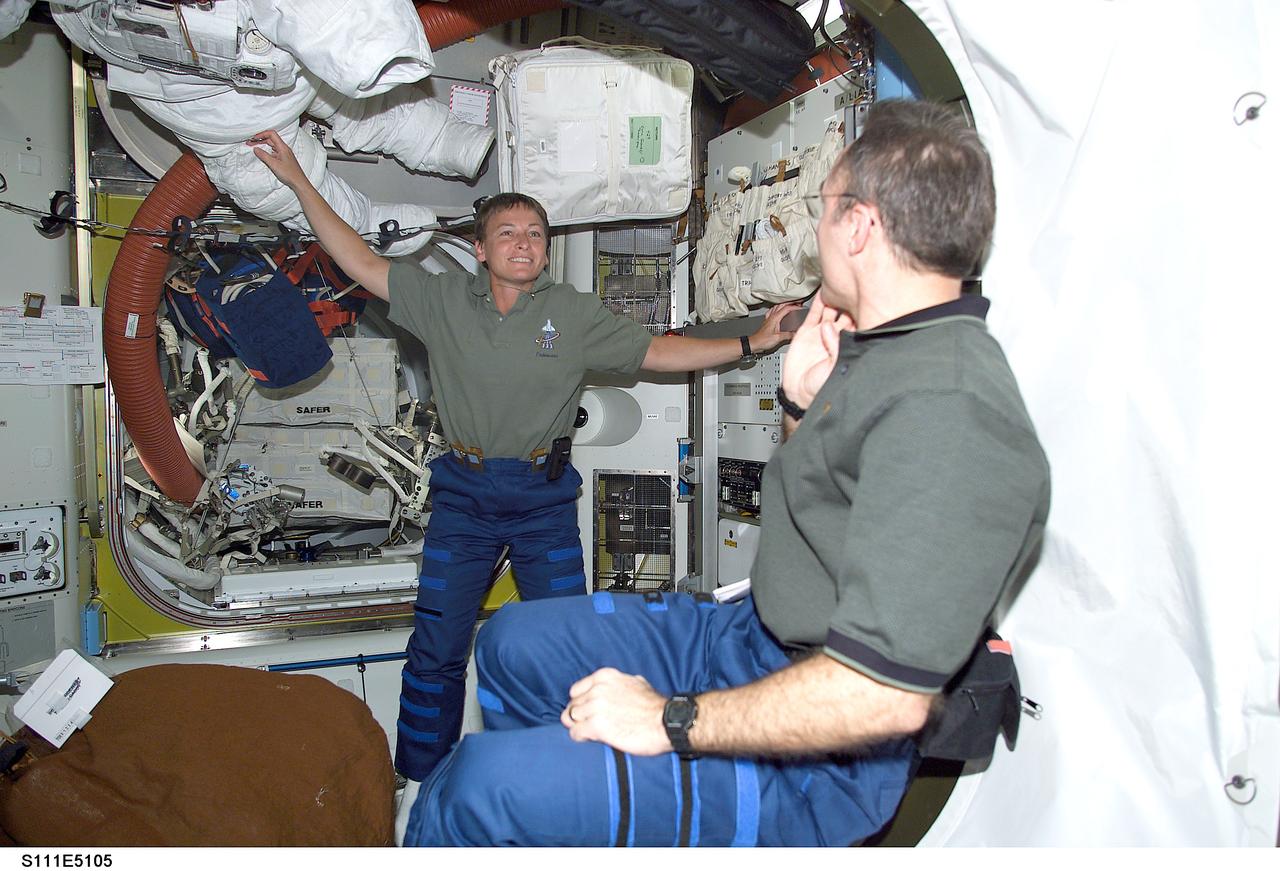 STS111-E-5105 (7 June 2002) --- Astronauts Peggy A. Whitson (background), Expedition Five flight engineer, and Carl E. Walz, Expedition Four flight engineer, are photographed on the International Space Station (ISS). The two are in the process of changing roles.