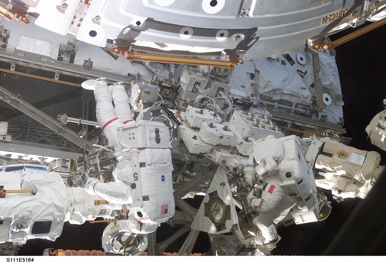 STS111-E-5164 (11 June 2002) --- Astronauts Franklin R. Chang-Diaz (left) and Philippe Perrin, both STS-111 mission specialists, work in tandem on the second scheduled session of extravehicular activity (EVA) for the STS-111 mission. During the spacewalk, Chang-Diaz and Perrin attached power, data and video cables from the International Space Station (ISS) to the Mobile Base System (MBS) and used a power wrench to complete the attachment of the MBS onto the Mobile Transporter (MT). Perrin represents CNES, the French Space Agency.