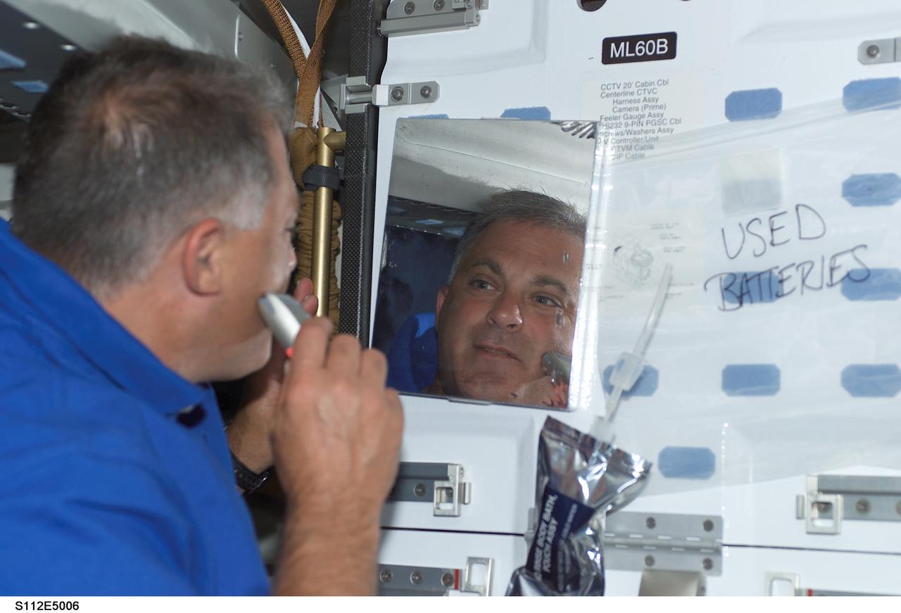 STS112-E-05006 (8 October 2002) --- Astronaut David A. Wolf, STS-112 mission specialist, uses a razor on his face during flight day two on the middeck of the Space Shuttle Atlantis.