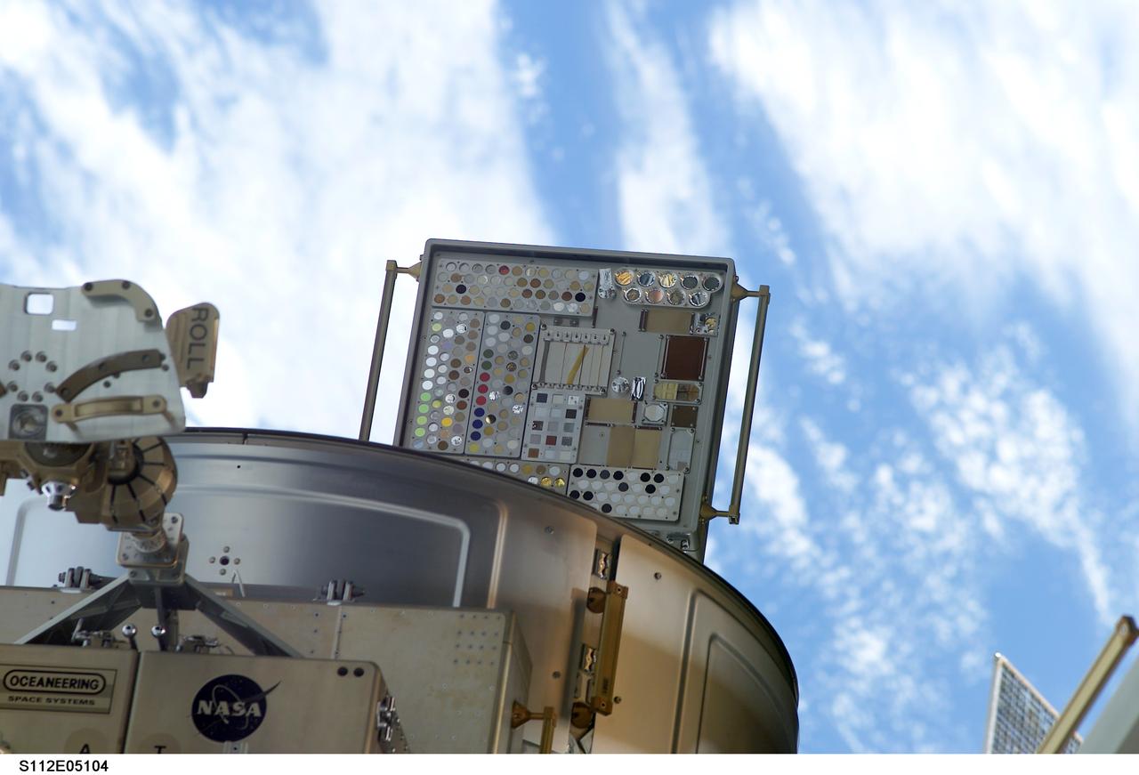 STS112-E-05104 (10 October 2002) --- Backdropped by a blue and white Earth, the Materials International Space Station Experiment (MISSE) and a portion of the Quest Airlock are visible. MISSE collects information on how different materials weather in the environment of space.