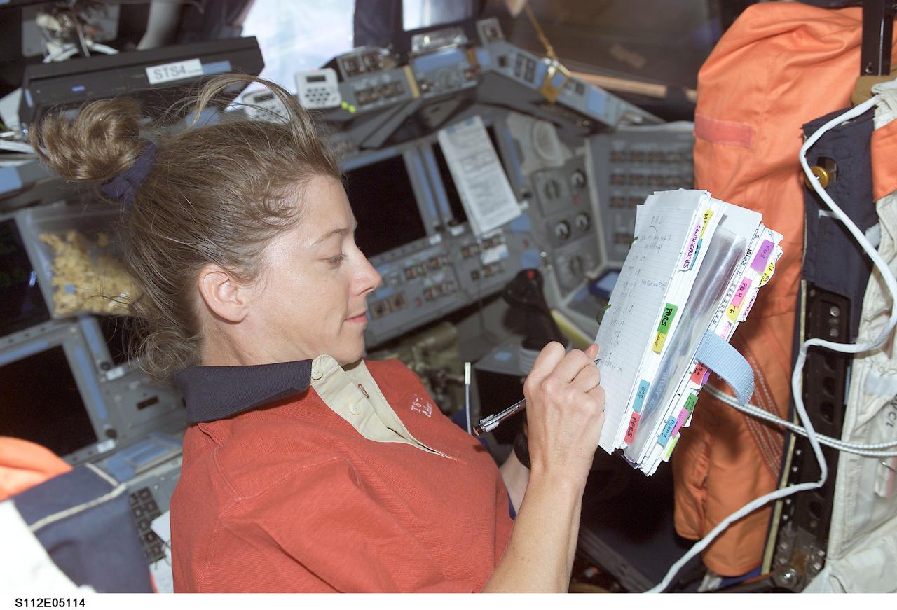 STS112-E-05114 (10 October 2002) --- Astronaut Pamela A. Melroy, STS-112 pilot, looks over a procedures checklist on the flight deck of the Space Shuttle Atlantis.