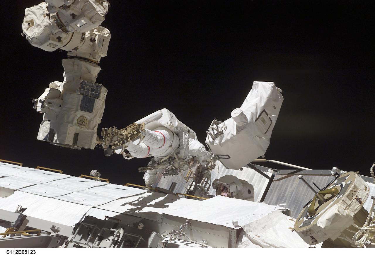 STS112-E-05123 (10 October 2002) --- Astronaut David A. Wolf, STS-112 mission specialist, anchored to the end of the Canadarm2, works on the Starboard One (S1) Truss, newly installed on the International Space Station (ISS). Astronaut Piers J. Sellers (partially obscured), mission specialist, worked in tandem with Wolf during the spacewalk. STS-112&#0146;s first session of extravehicular activity (EVA) lasted 7 hours and 1 minute.