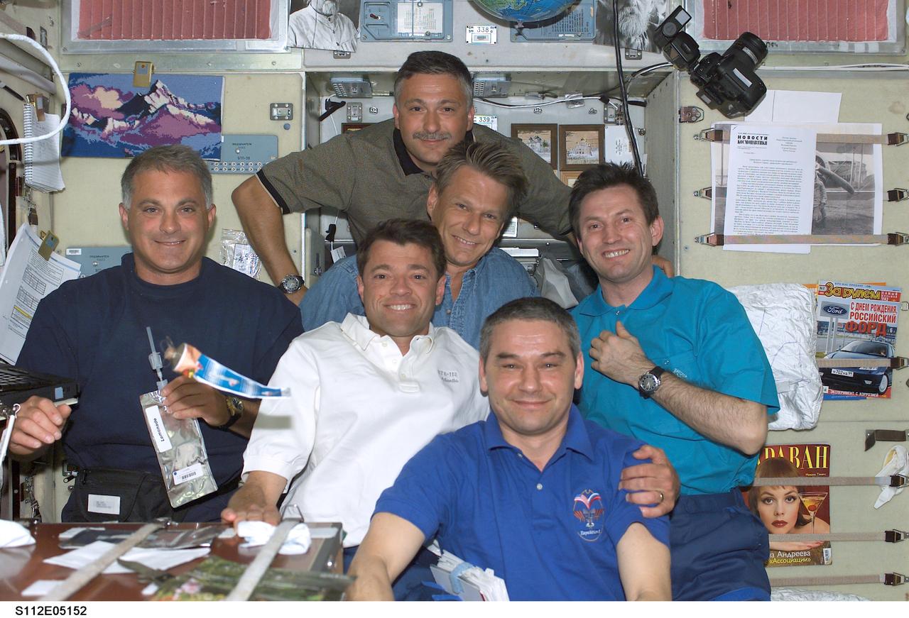 STS112-E-05152 (11 October 2002) --- The STS-112 and Expedition Five crewmembers share a meal in the Zvezda Service Module on the International Space Station (ISS). Pictured, from the left (foreground), are astronauts David A. Wolf, STS-112 mission specialist; Jeffrey S. Ashby, STS-112 mission commander; and cosmonaut Valery G. Korzun, Expedition Five mission commander. Pictured, from the left (back row), are cosmonaut Fyodor N. Yurchikhin; astronaut Piers J. Sellers, both STS-112 mission specialists; and cosmonaut Sergei Y. Treschev, Expedition Five flight engineer. Korzun, Treschev and Yurchikhin represent Rosaviakosmos.