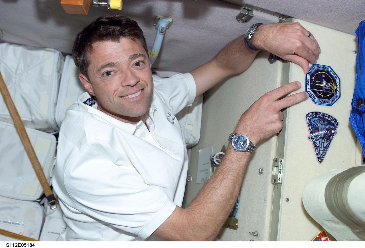 STS112-E-5184 (11 October 2002) --- Continuing a tradition for visiting shuttle crew commanders, astronaut Jeffrey Ashby, STS-112 commander, posts the mission insignia onboard the International Space Station (ISS).