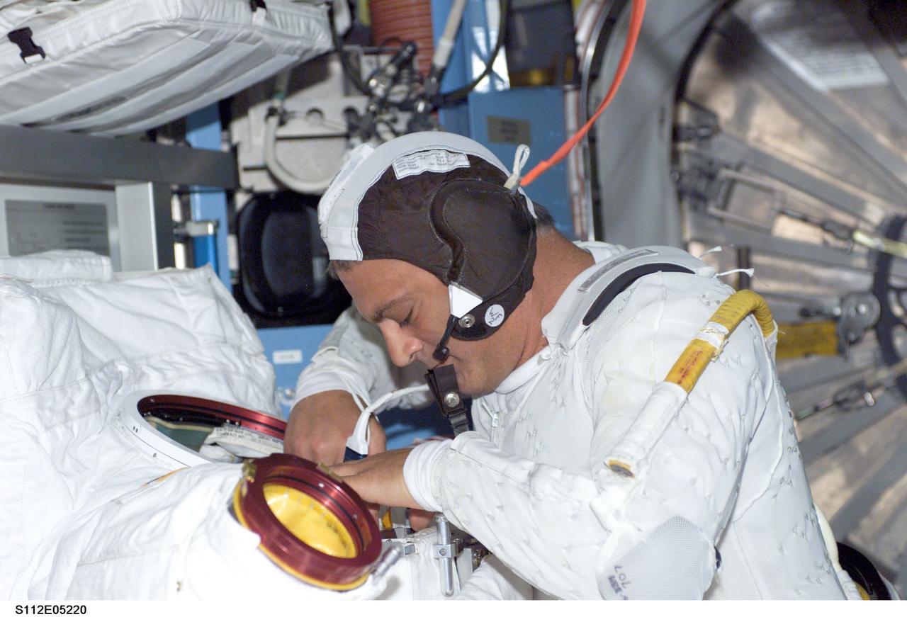 STS112-E-5220 (12 October 2002) --- Astronaut David A. Wolf, STS-112 mission specialist, gets his extravehicular mobility unit (EMU) spacesuit ready for the second scheduled spacewalk of the mission.