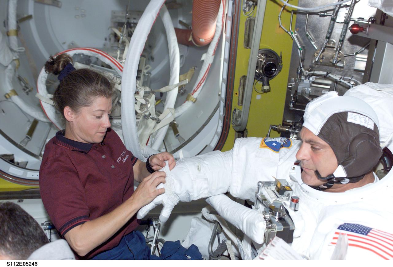 STS112-E-5246 (12 October 2002) --- Astronaut Pamela Melroy, STS-112 pilot, assists astronaut David A. Wolf with  his extravehicular mobility unit (EMU) spacesuit prior to the mission's second scheduled spacewalk.